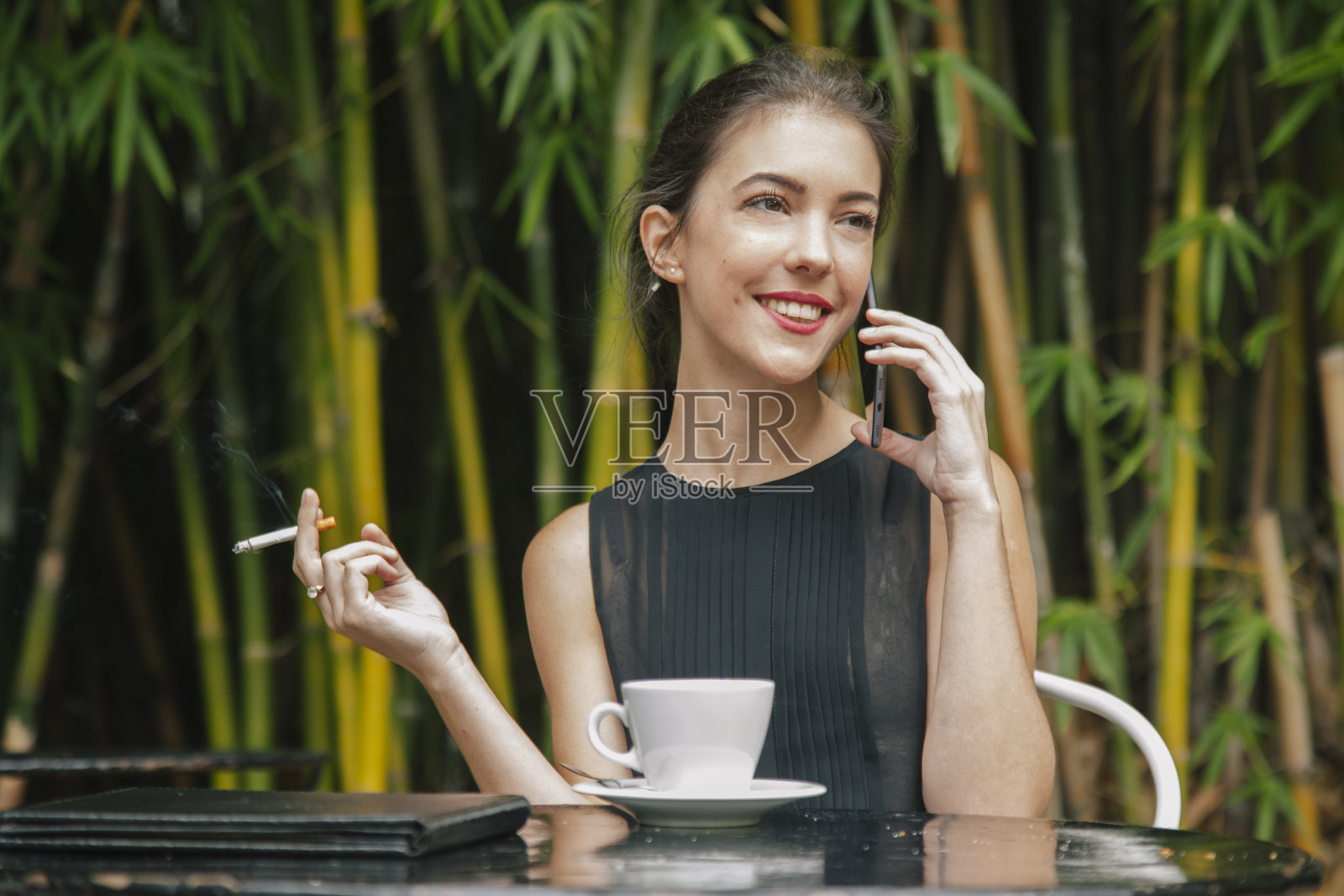 一个女人在打电话，抽烟，喝咖啡照片摄影图片