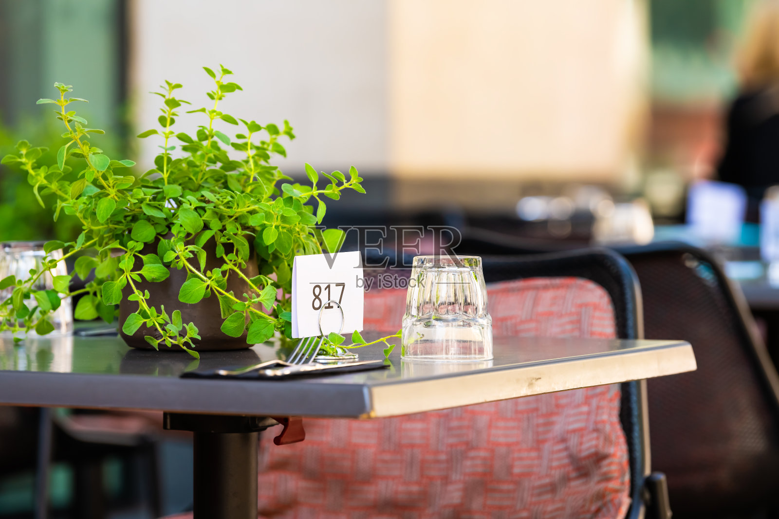 玻璃杯子倒挂在餐厅桌子上的特写，外面的街道咖啡馆有订单号标志和绿色植物，在夏天没有人空院子照片摄影图片