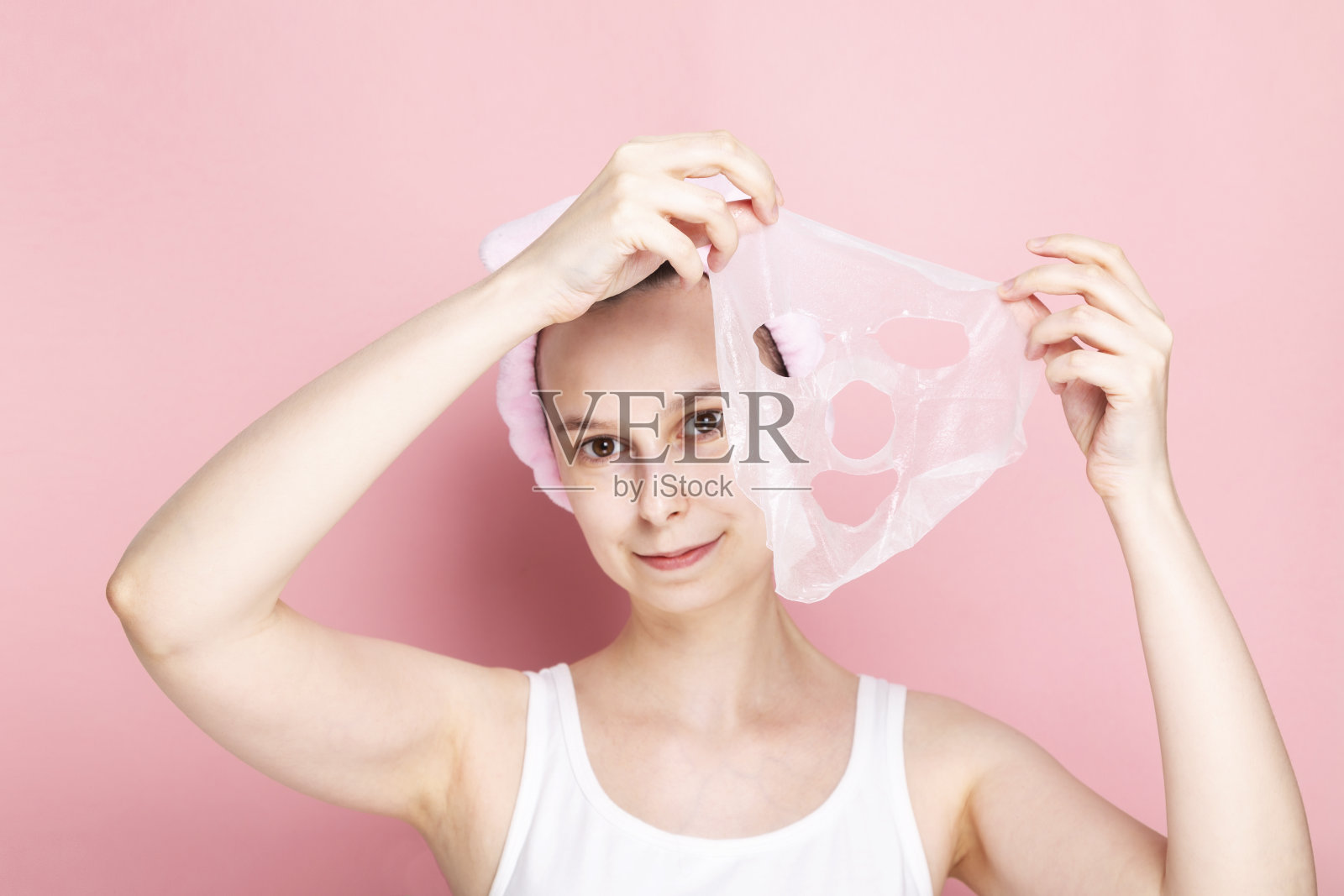 女人拿着化妆品面膜在粉红色的背景照片摄影图片
