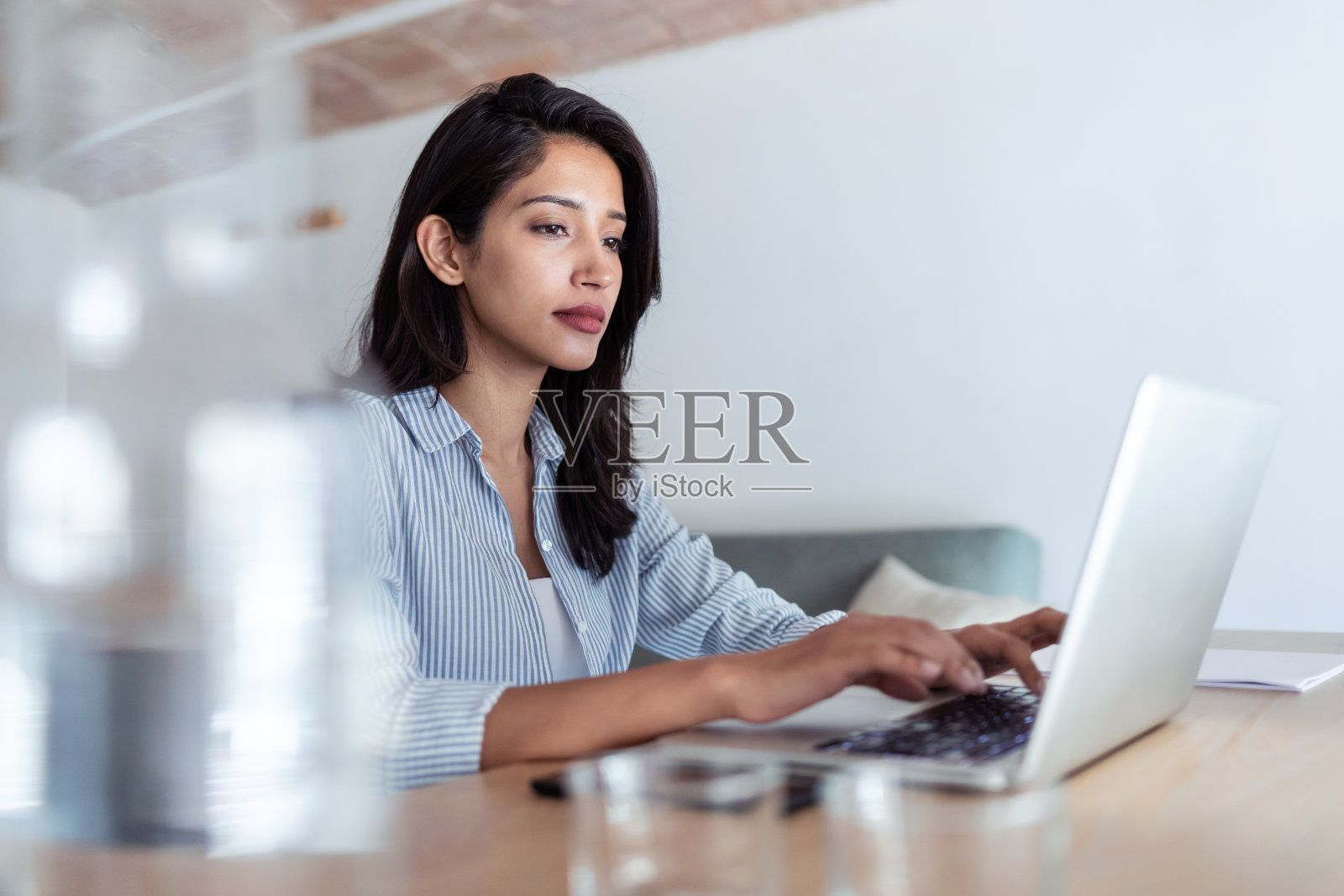 优雅的年轻商务女性在办公室用她的笔记本电脑工作。照片摄影图片