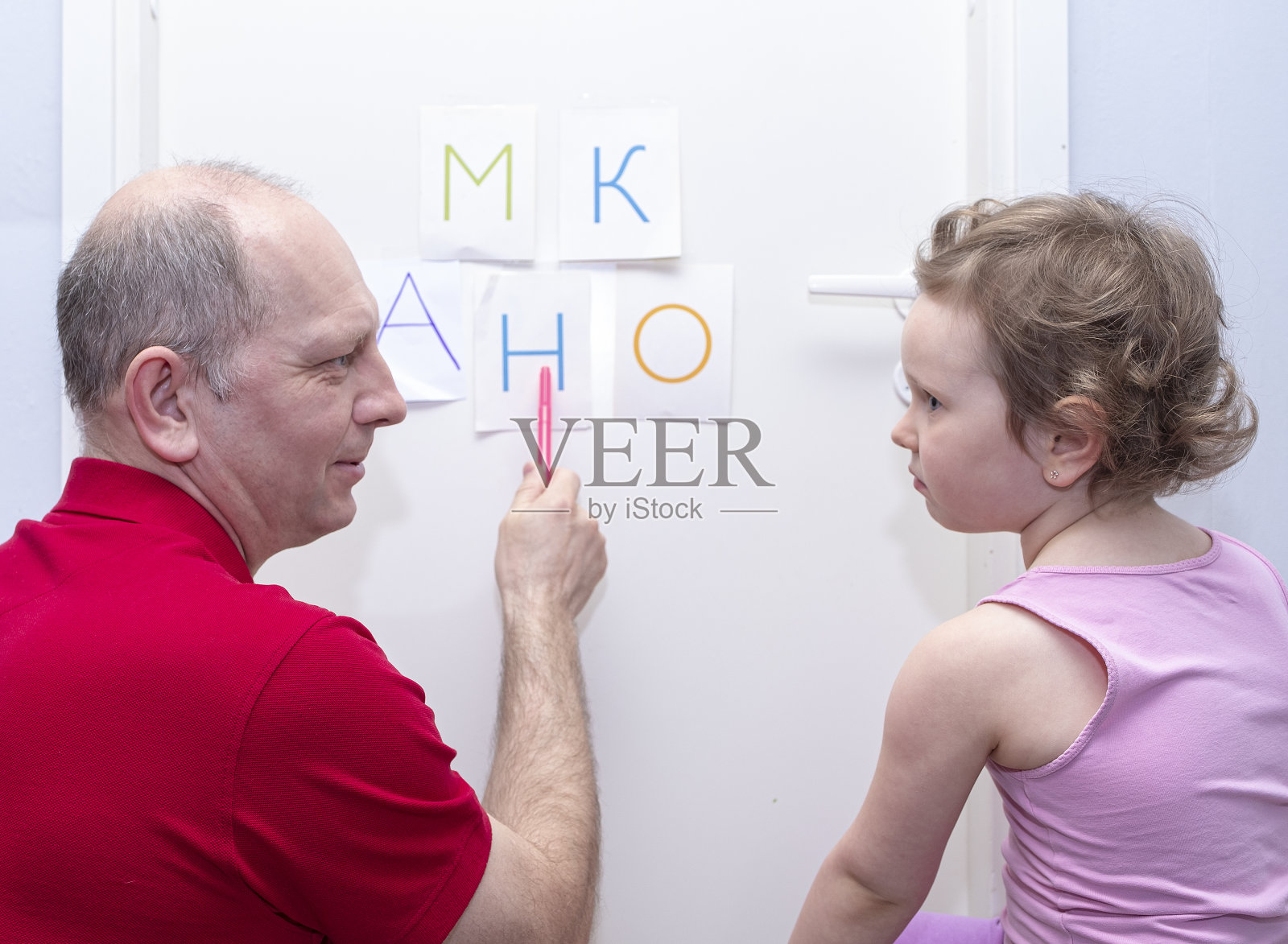 一个男人，一个父亲，帮助一个小女儿学习字母表。照片摄影图片