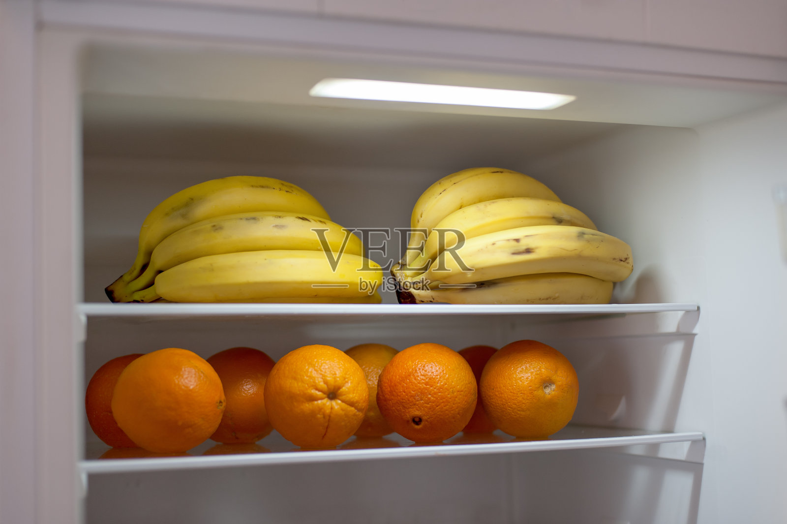 香蕉和橙子放在开放式冰箱里。新鲜维生素水果早餐照片摄影图片