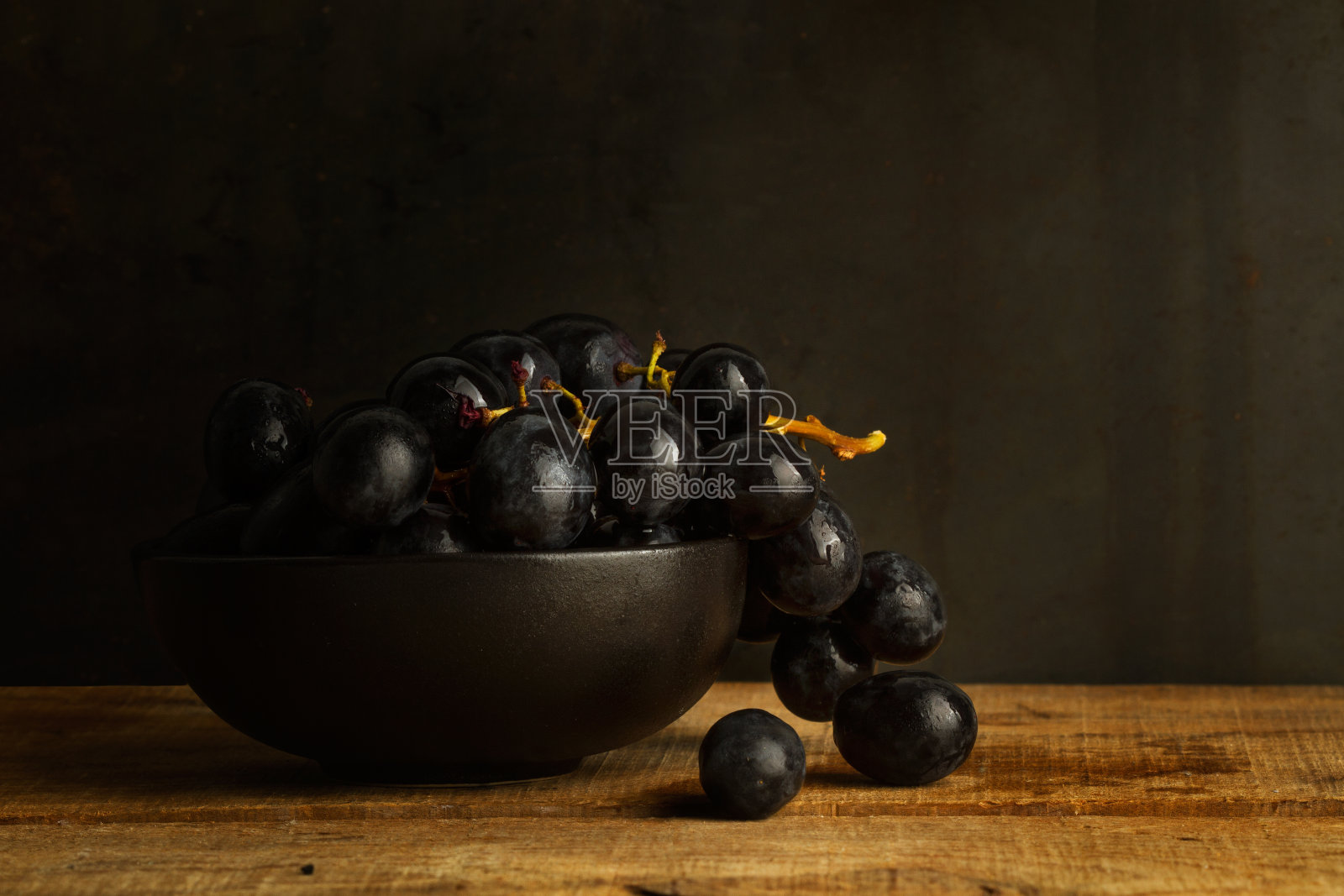 一串黑葡萄放在黑色陶瓷碗里照片摄影图片