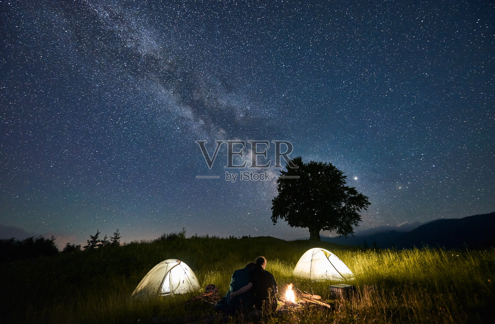 朋友旅行者花时间在山上围坐篝火露营在美丽的星空下照片摄影图片