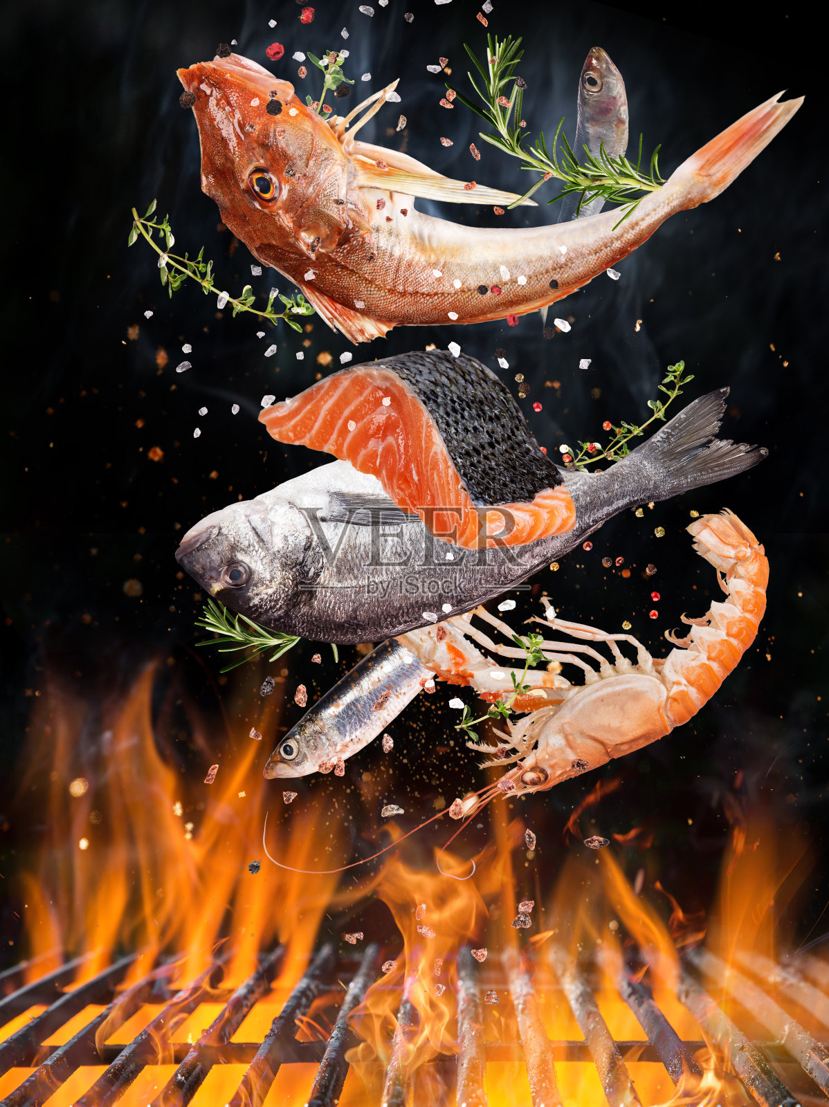 美味的鱼在火焰中飞舞在铸铁炉排上。照片摄影图片