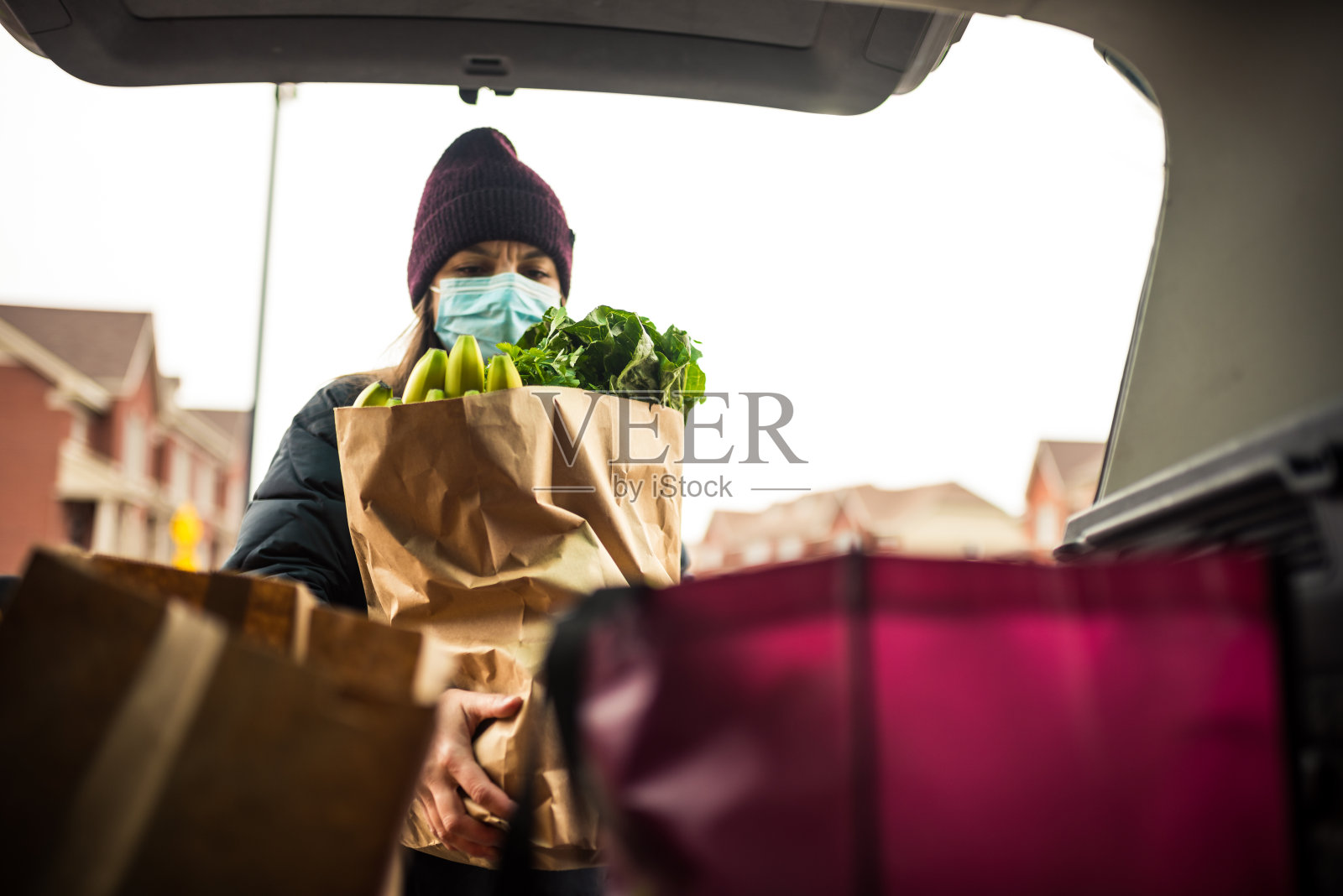 成熟的女人从汽车后备箱里卸下杂货照片摄影图片