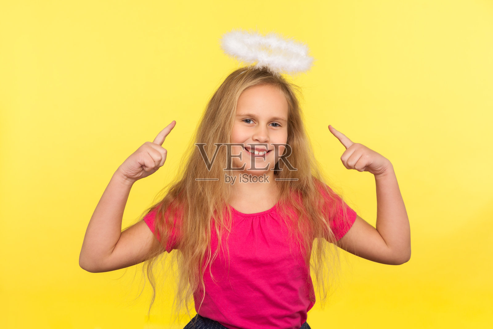 可爱的快乐小女孩的肖像与长长的金发指向天使的光环头顶，看着相机与牙齿的微笑照片摄影图片