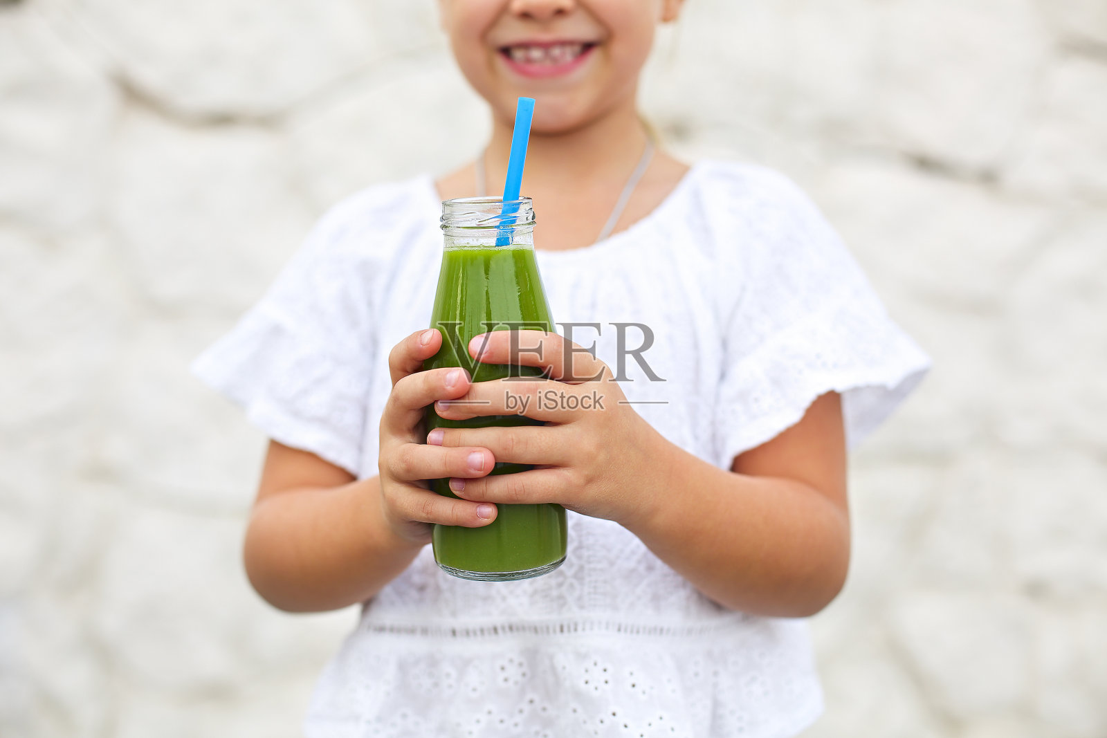 一个小女孩正在户外用稻草喝新鲜的绿色果汁照片摄影图片