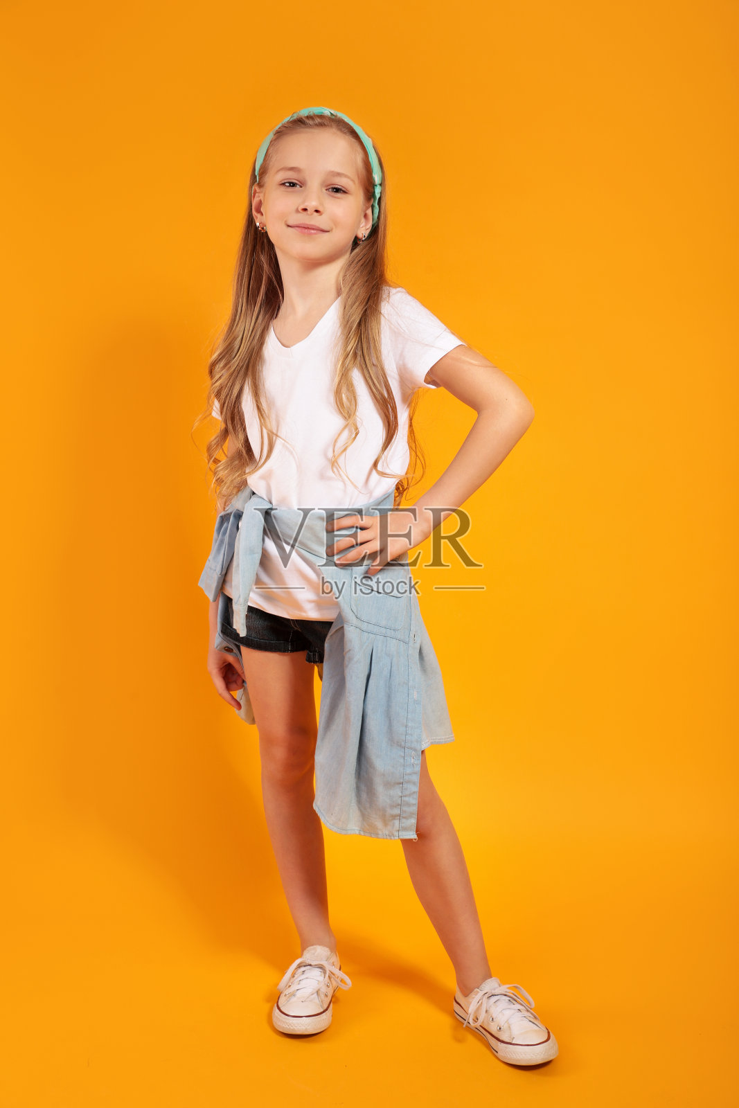 一个快乐的小女孩穿着夏天的衣服在黄色的背景上摆姿势。假期的概念照片摄影图片