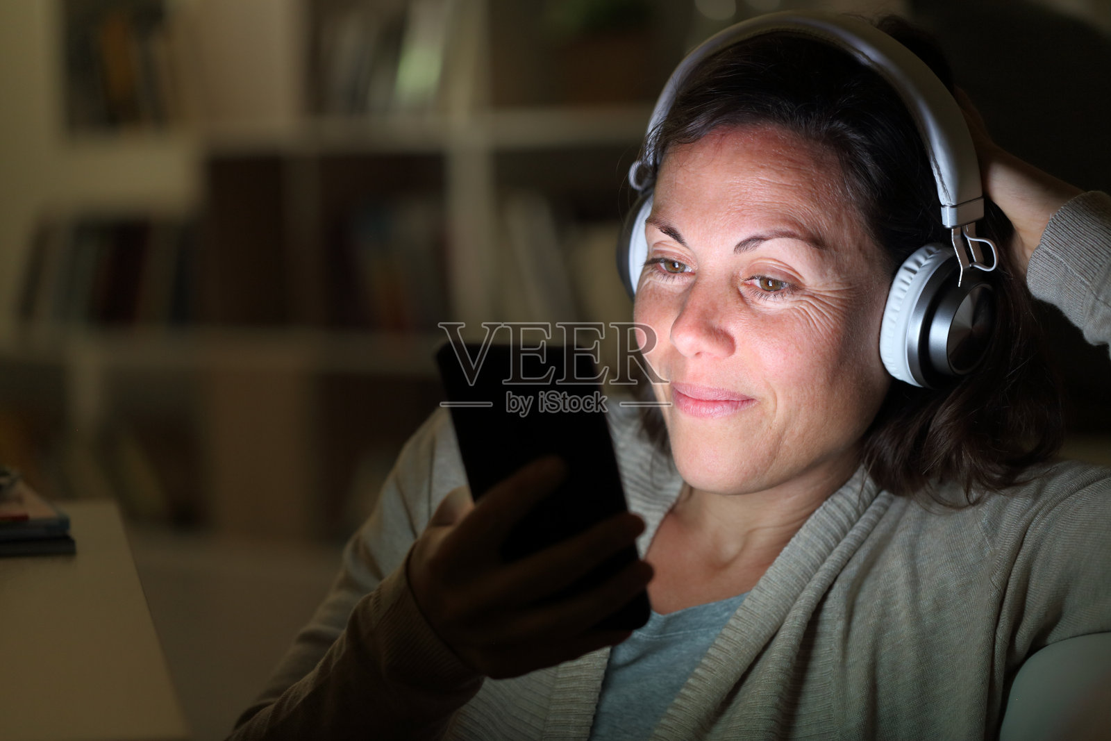 成年女性戴耳机在手机上听音乐照片摄影图片