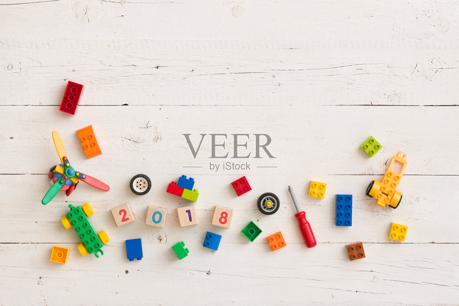 俯视图儿童玩具，彩色塑料砖和木制立方体与数字2018在白色木制背景。照片摄影图片