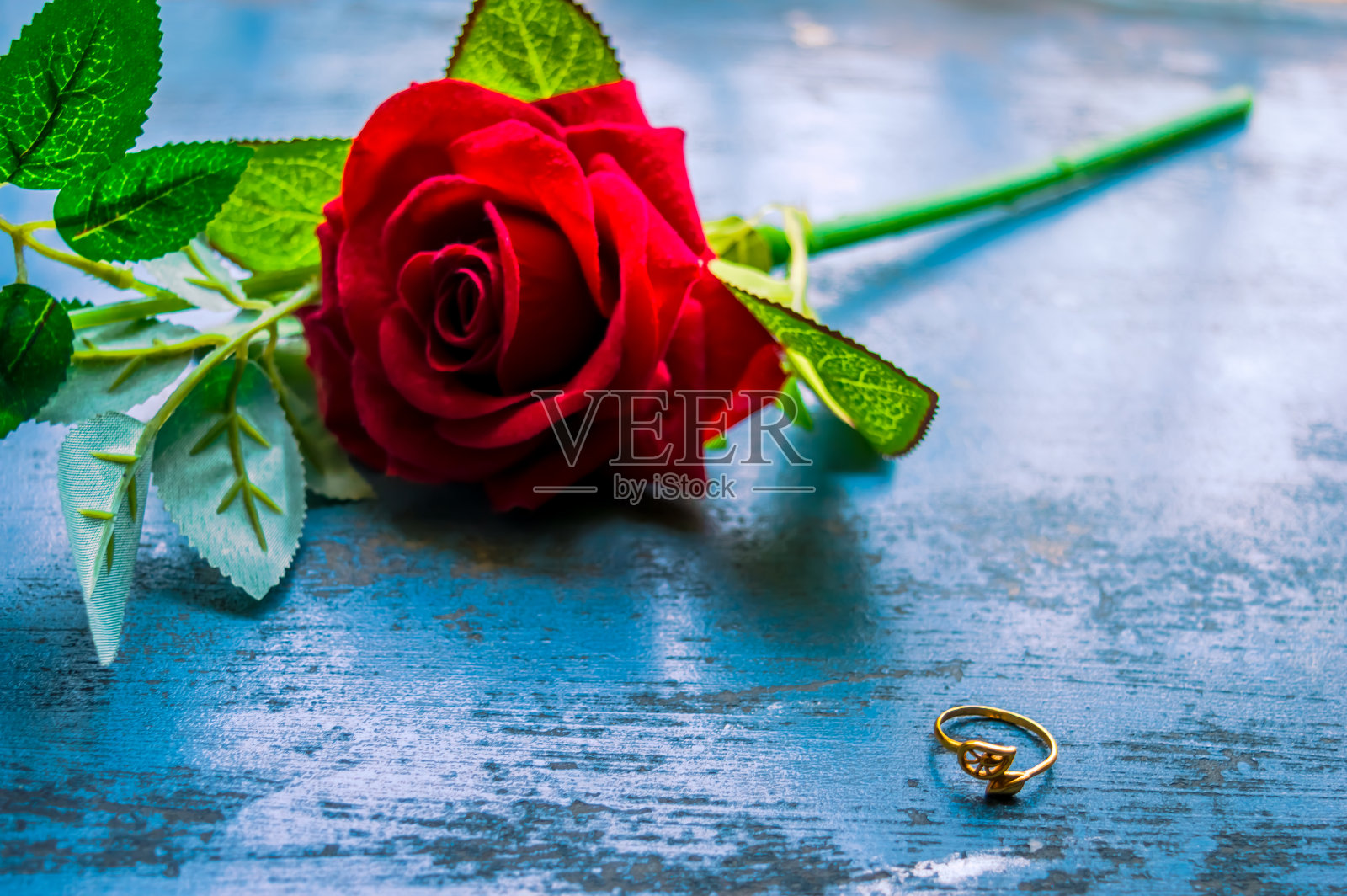 靠近乡村金属地板上的金订婚戒指珠宝。柔和的焦点浪漫的红色玫瑰花的背景。爱情提议或提议概念的情人节婚礼和假期。副本的空间。照片摄影图片