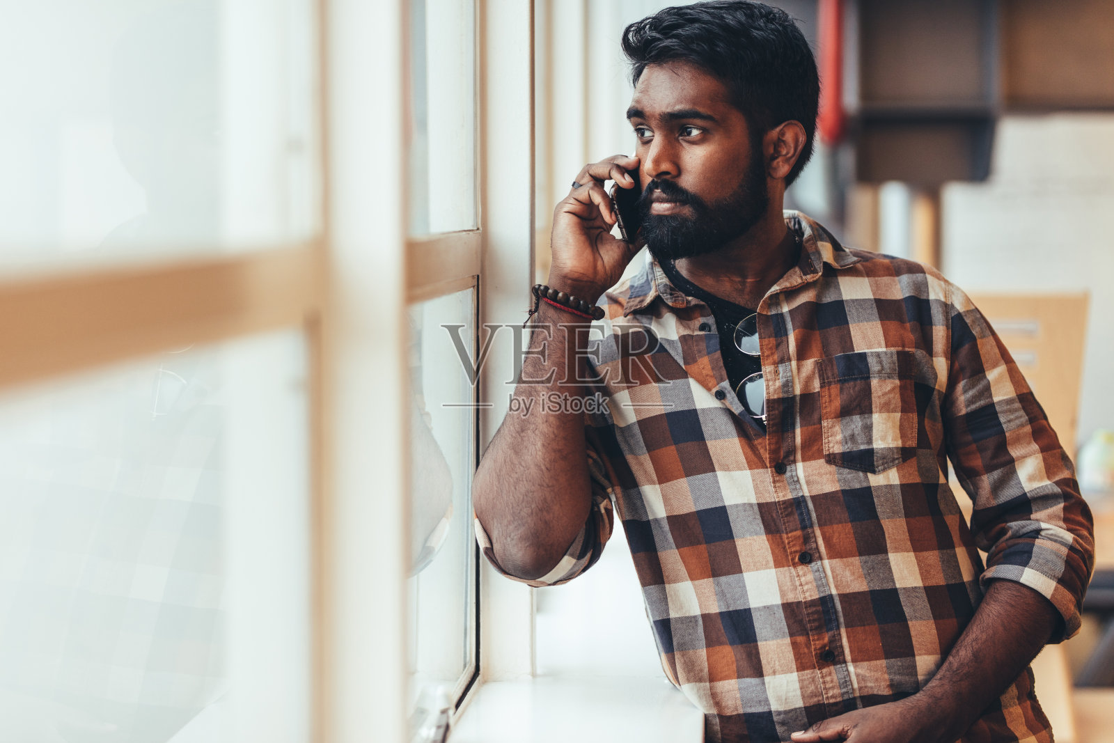 一名男子站在窗边用手机聊天照片摄影图片