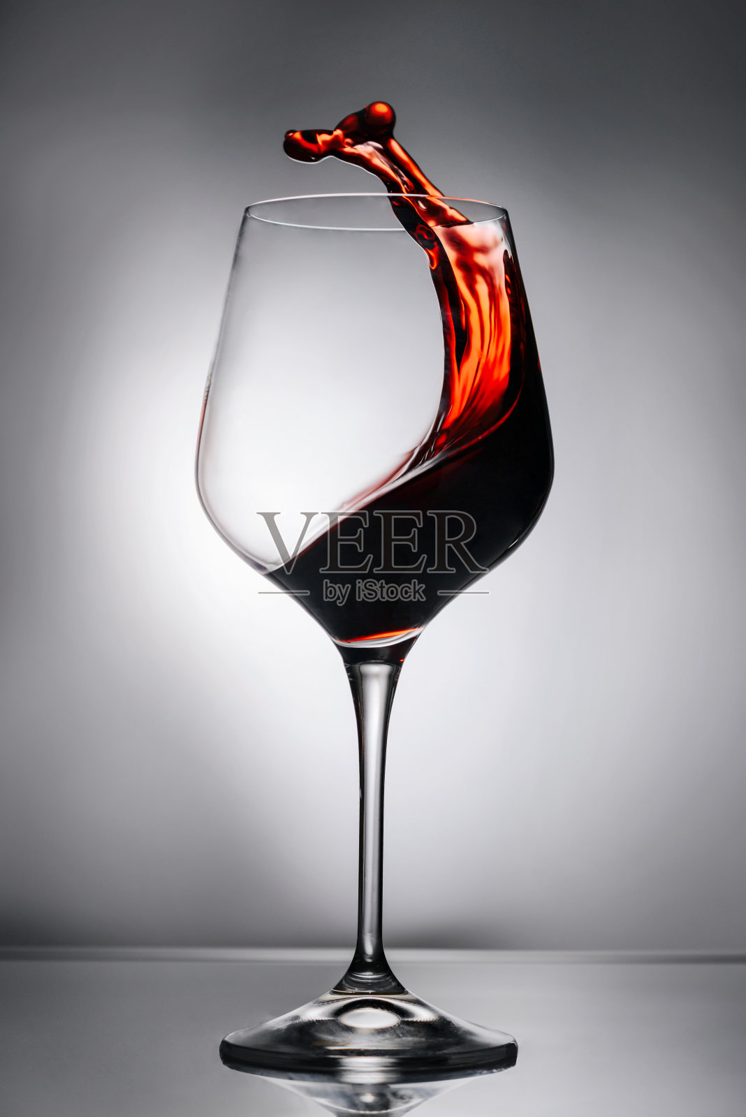 将红酒倒入玻璃杯中，洒在玻璃杯表面。照片摄影图片