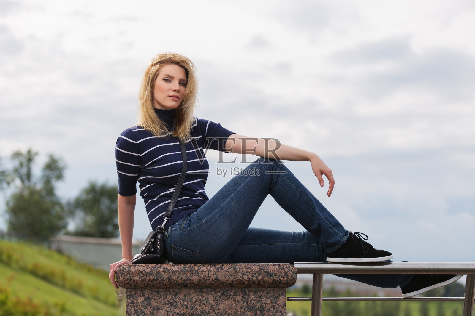 年轻时尚的女人在条纹高领t恤坐在栏杆上照片摄影图片