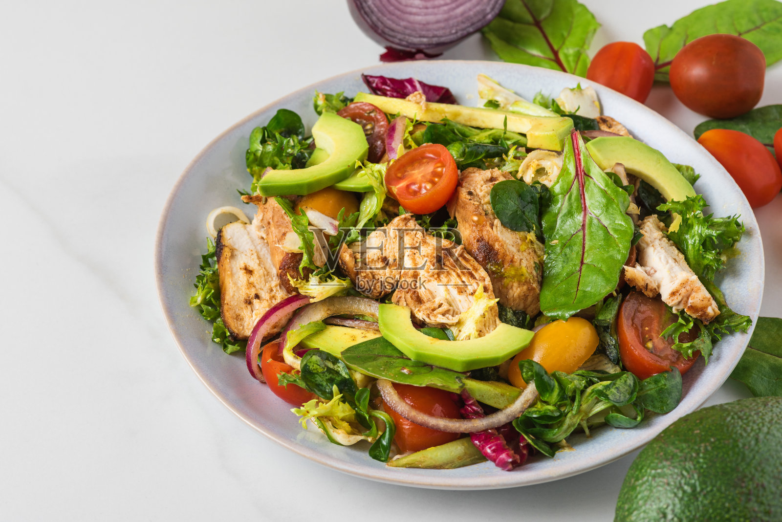 健康沙拉配烤鸡胸肉，牛油果，洋葱和番茄，白色背景。健康的减肥食品照片摄影图片