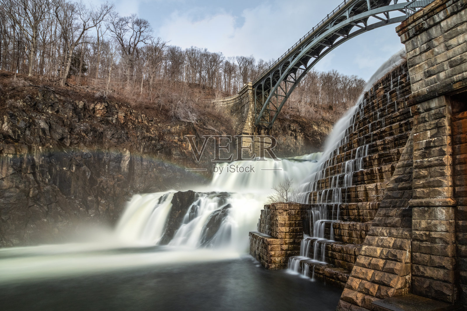 水流从新克罗顿大坝上倾泻而下，桥在瀑布上呈拱形照片摄影图片