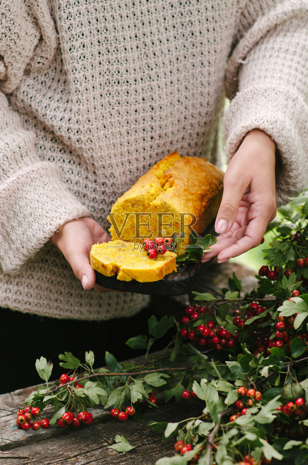 秋天的南瓜面包派。自然中的乡村风格摄影。一个穿着毛衣的女人手里拿着一个派。照片摄影图片