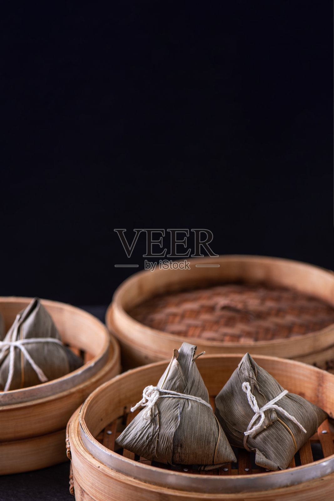 汤圆、粽子——端午节，黑色背景的木桌上蒸着一串中国传统食物。照片摄影图片