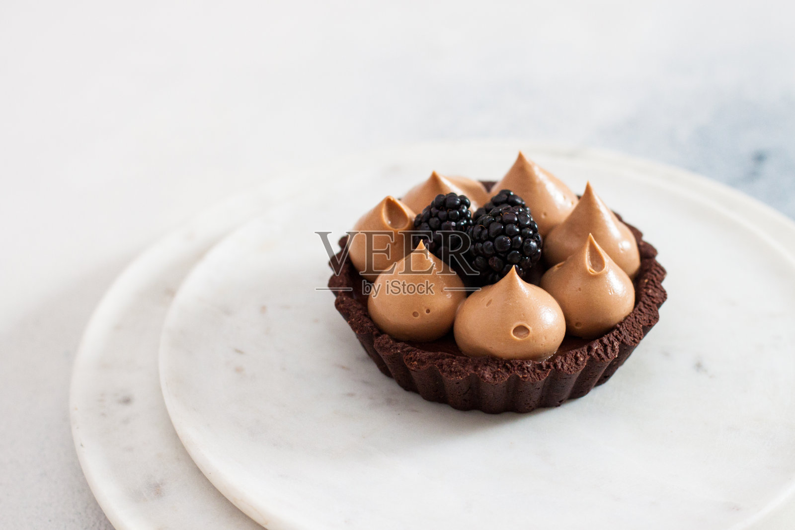 迷你巧克力挞配焦糖奶油和新鲜黑莓。纯白色背景。照片摄影图片