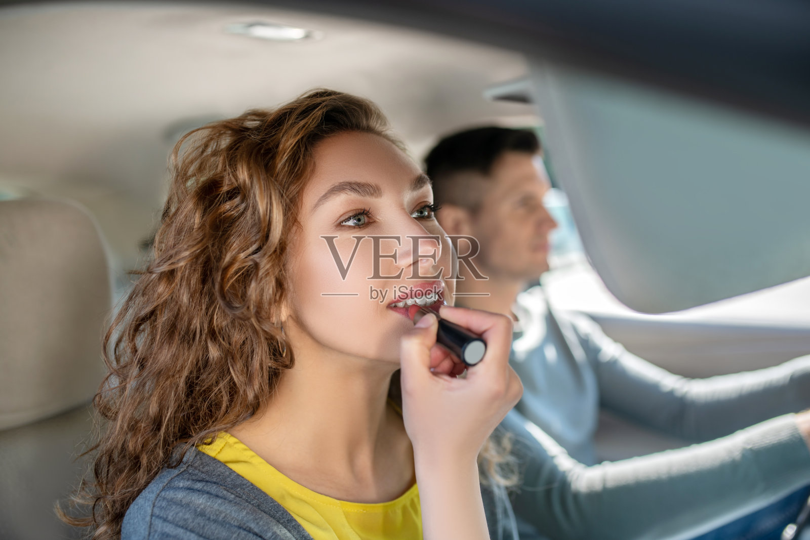 美丽的女人在汽车乘客座位上画嘴唇照片摄影图片