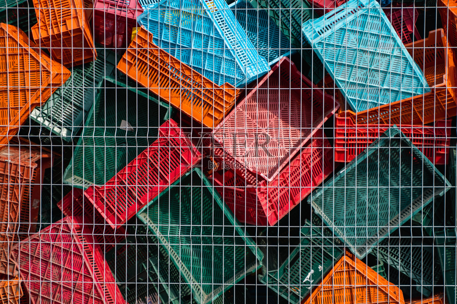 废弃的塑料盒子放在仓库的金属网围栏后面作为垃圾。照片摄影图片