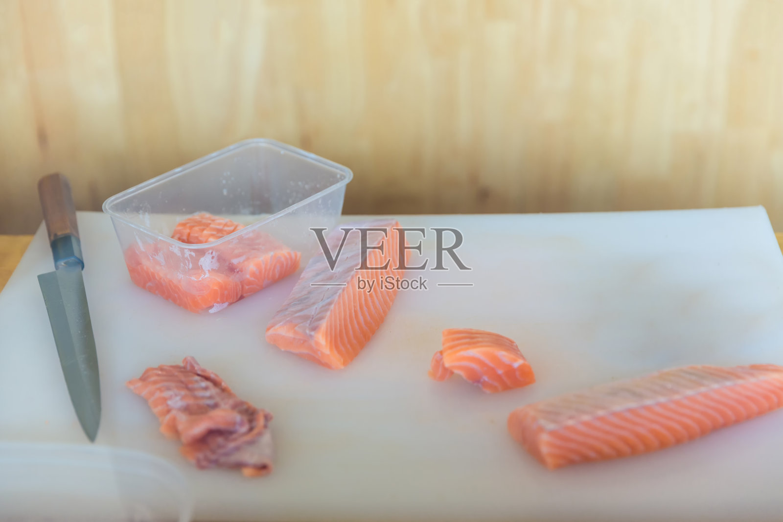 切板上的新鲜鲑鱼，餐厅的日本厨师切生鲑鱼，海鲜菜肴的原料。厨师用刀切生鲑鱼。照片摄影图片