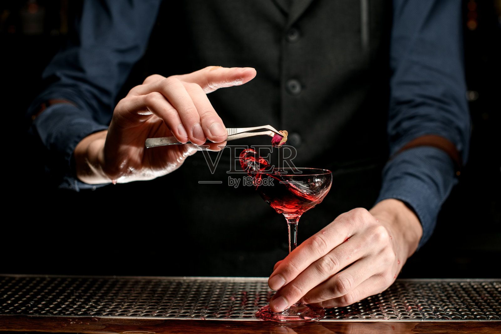 男酒保用喷溅酒装饰透明玻璃。照片摄影图片