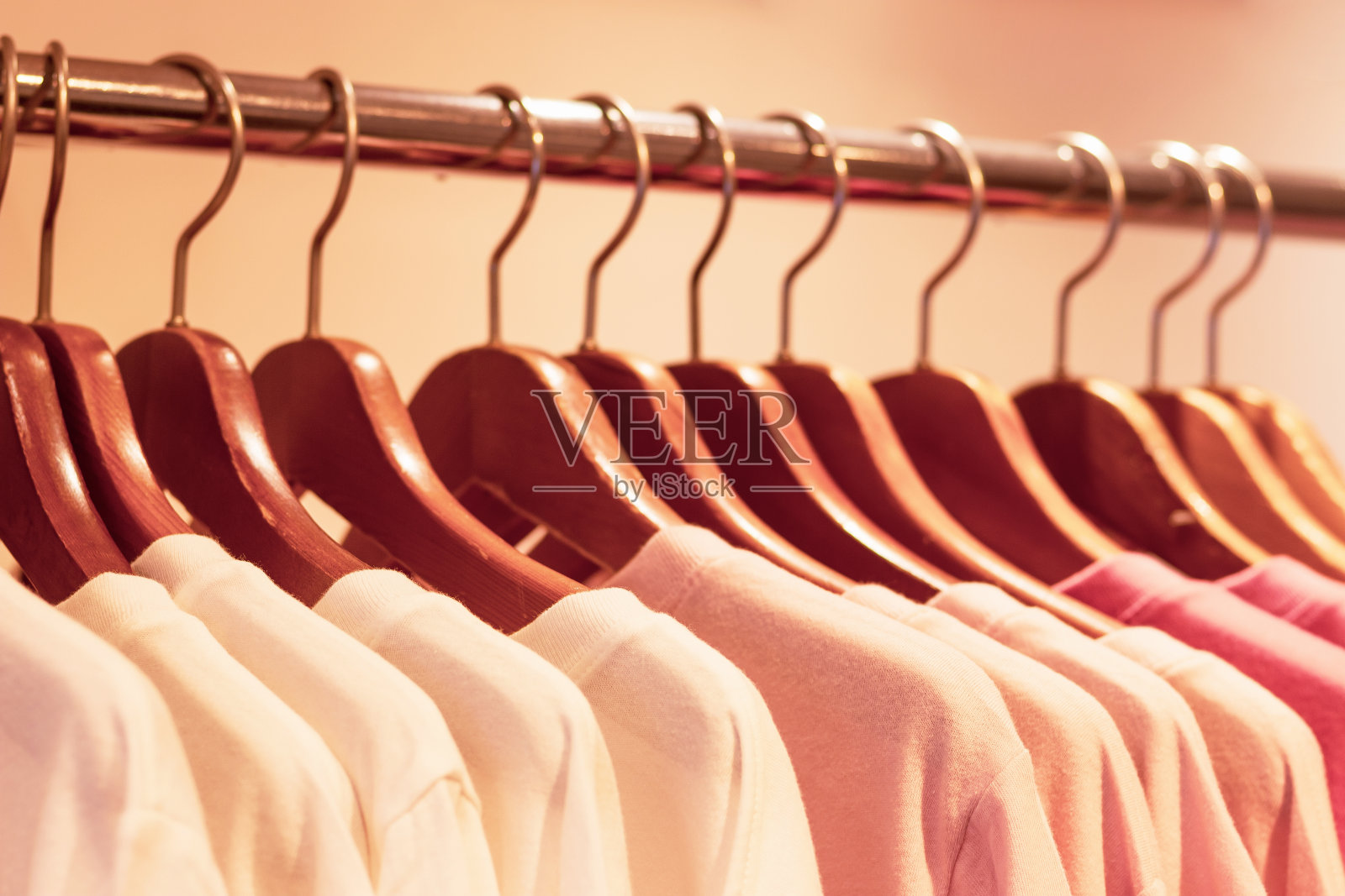 特写的粉红色针织毛衣挂在木制衣架在商店。照片摄影图片