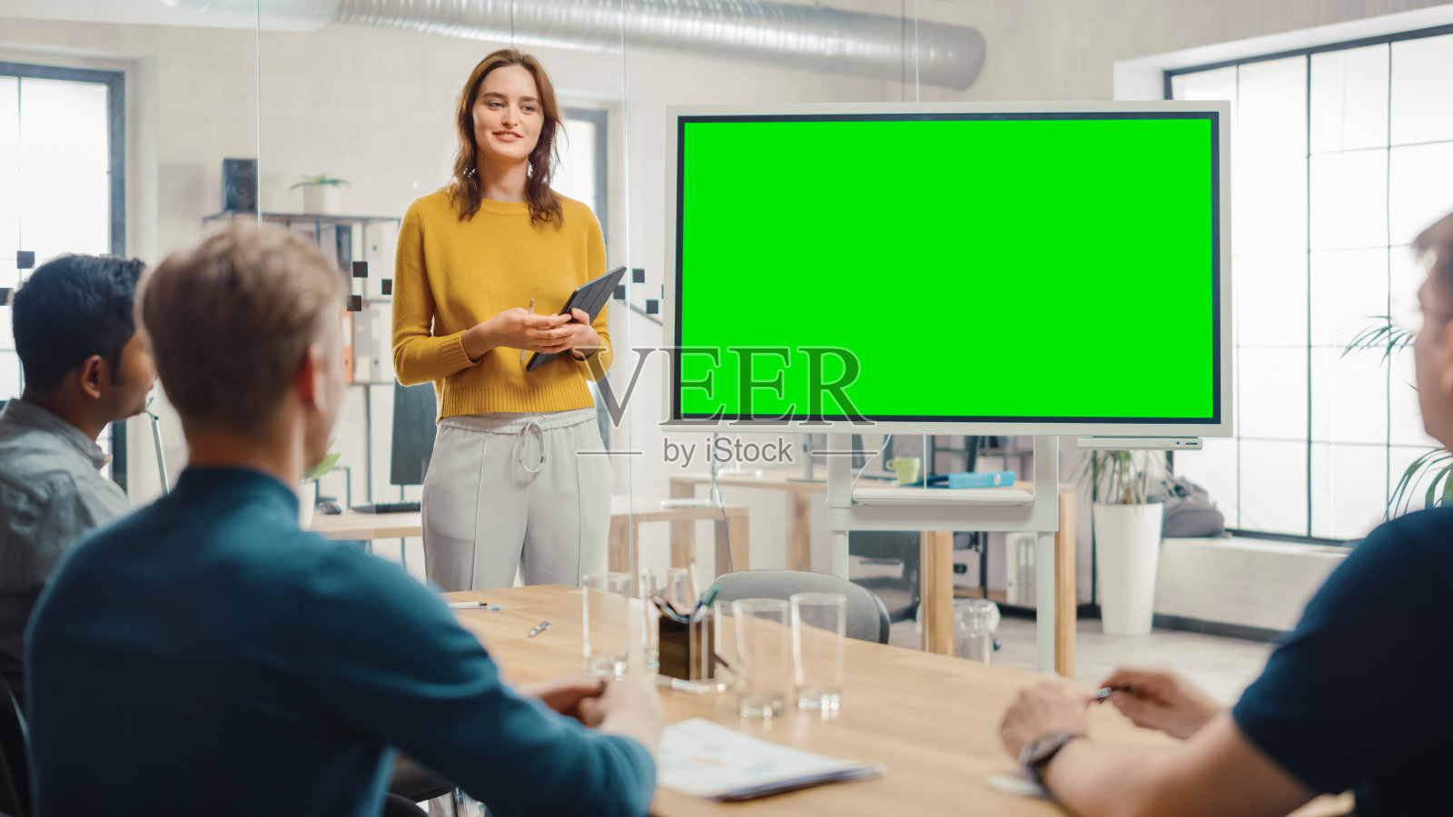 女项目经理为开发团队召开会议。她展示了绿色屏幕互动白板设备的商业规划概念。年轻人在创意办公室工作。照片摄影图片