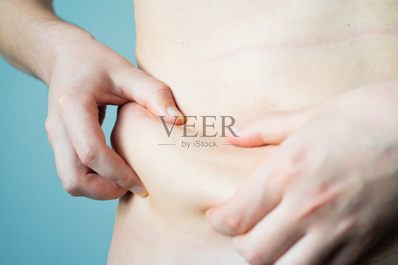 男人的手检查身体两侧和腹部的一层脂肪，特写。年轻人脆弱的身体需要锻炼、压力和训练照片摄影图片