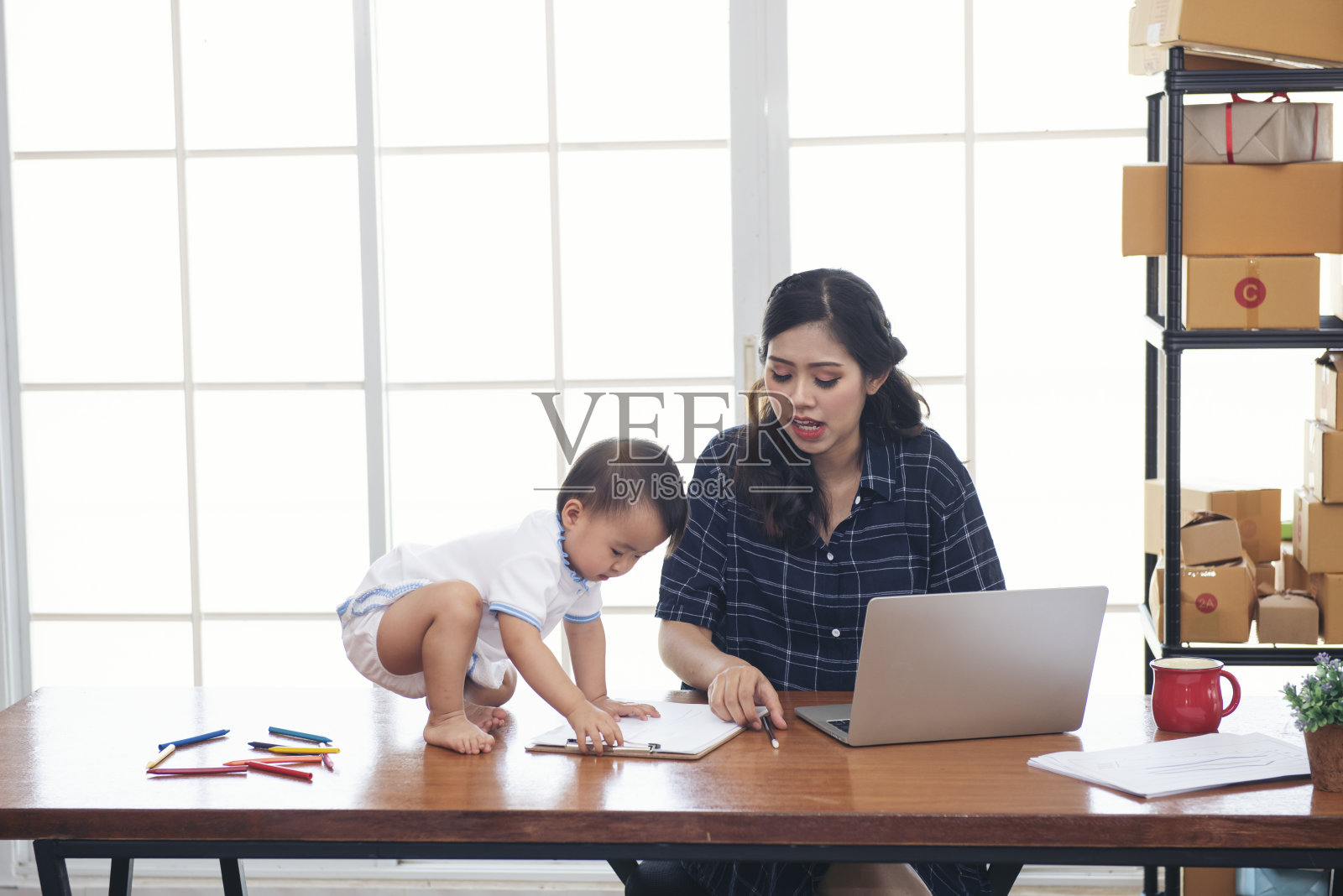 工作的亚洲母亲，婴儿，孩子和笔记本电脑在家办公。照片摄影图片