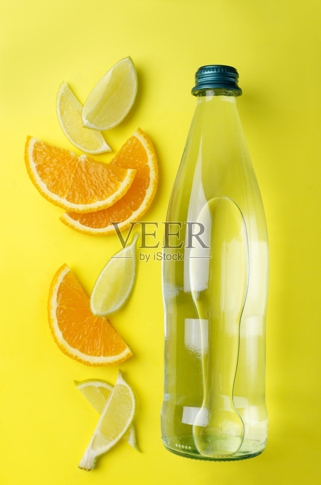 俯视图的玻璃瓶与柑橘新鲜的水。柠檬和橙子片，黄色背景上的一瓶饮料照片摄影图片