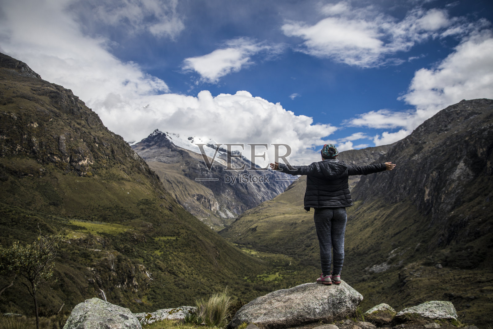 站在岩石上张开双臂站在群山中间的女人照片摄影图片