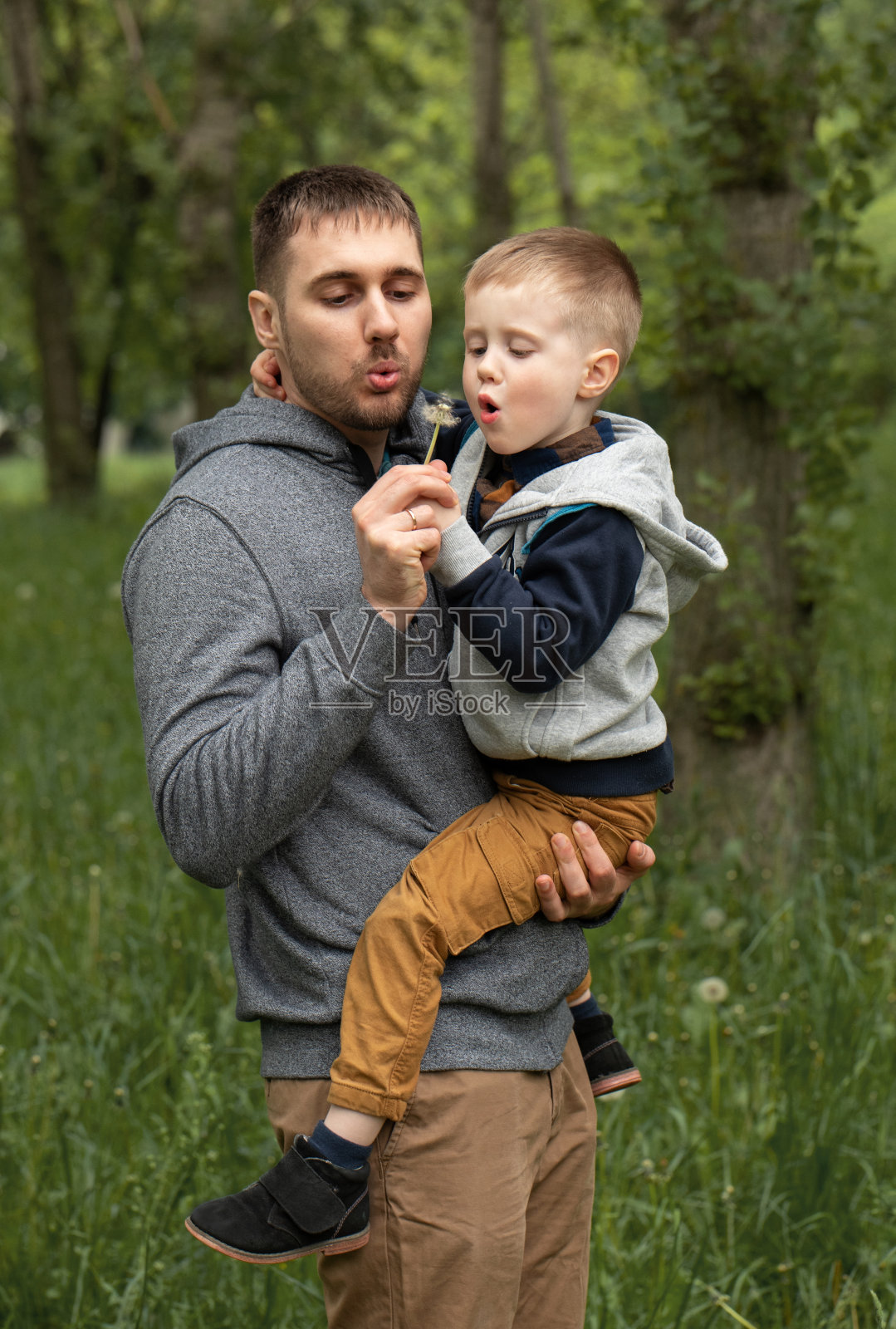 那男孩在他父亲的怀里。在公园里散步。照片摄影图片