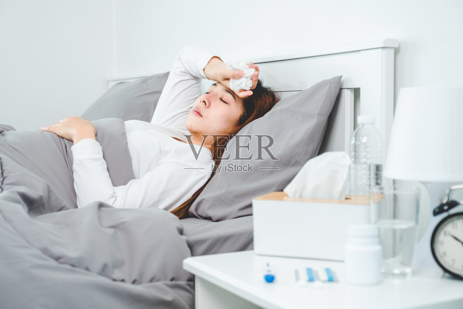 亚洲妇女流感和感冒，生病和睡在家里的床上。发热、咳嗽、擤鼻涕、用纸巾打喷嚏。感觉不适问题的治疗理念照片摄影图片