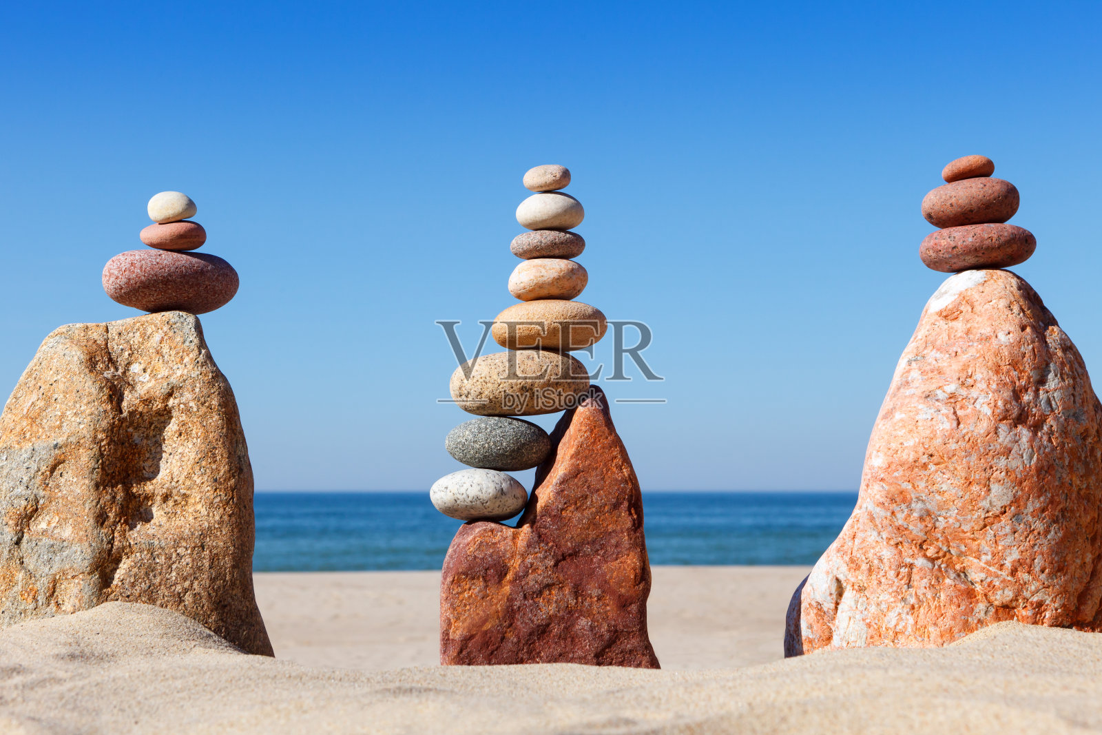 以大海为背景的海滩上的彩色卵石构成的岩石禅宗金字塔。照片摄影图片
