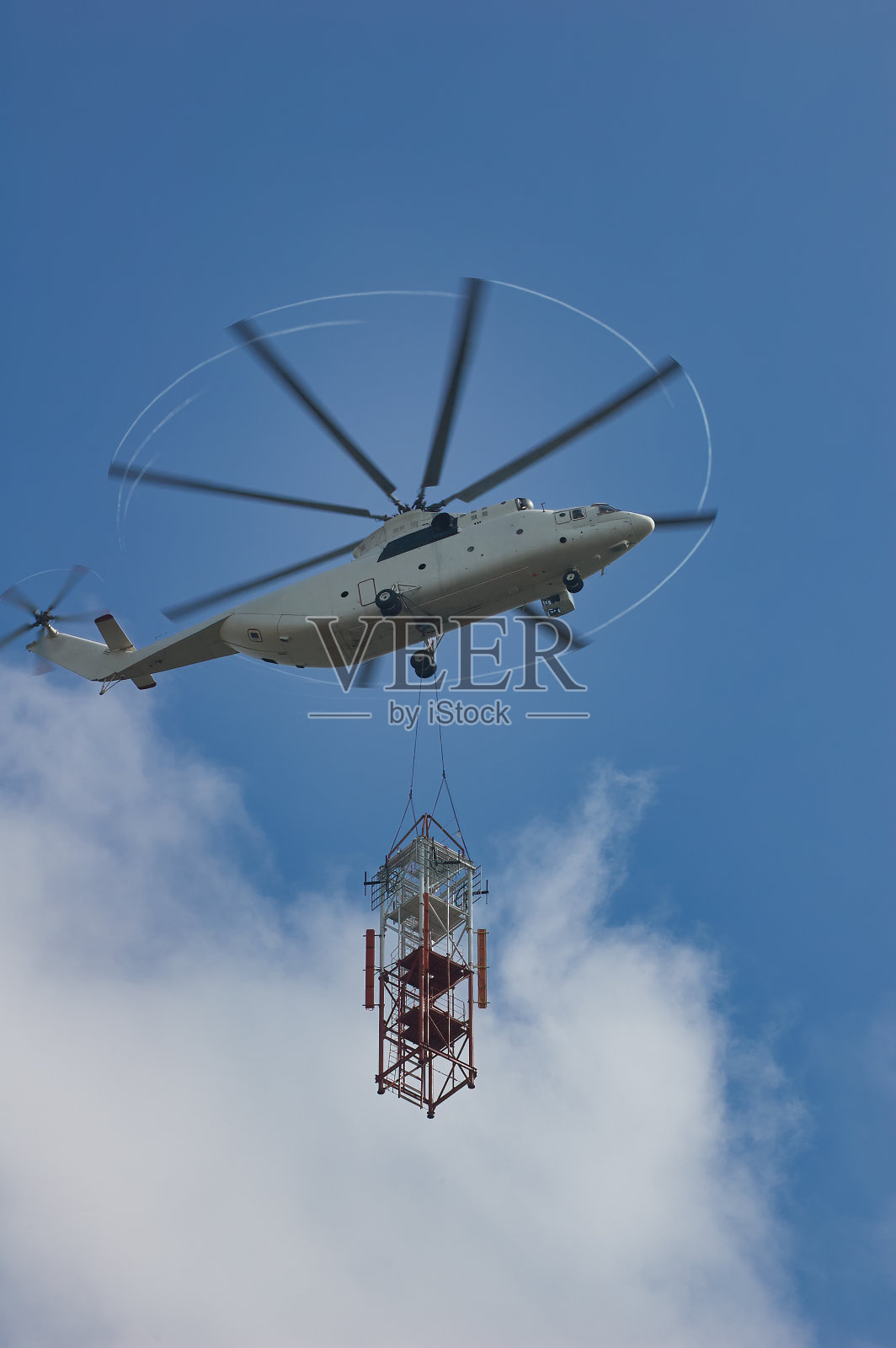 大型运输直升机为建筑工地运送零件。直升飞机在蓝天白云照片摄影图片