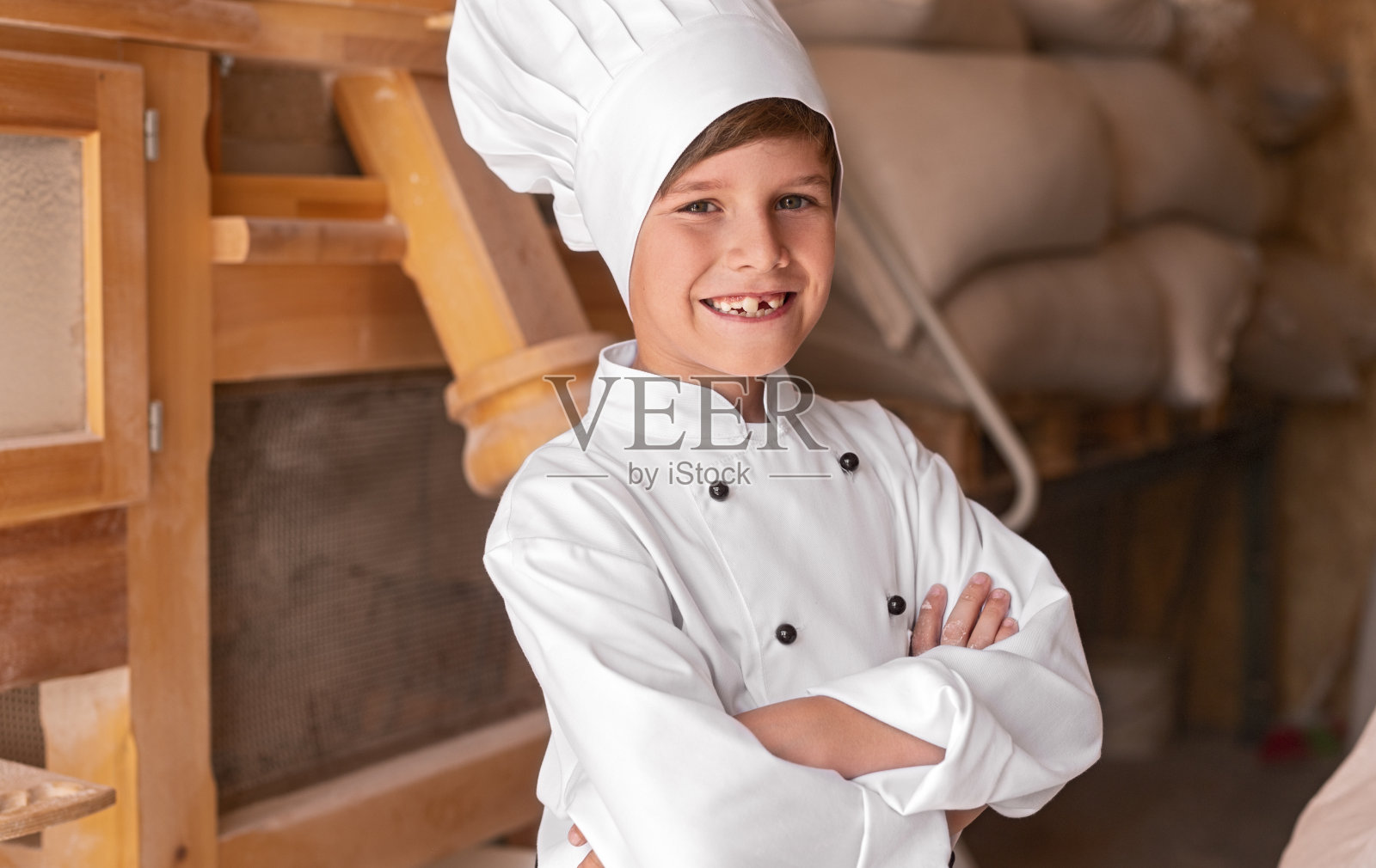 微笑的小厨师站在磨坊里照片摄影图片