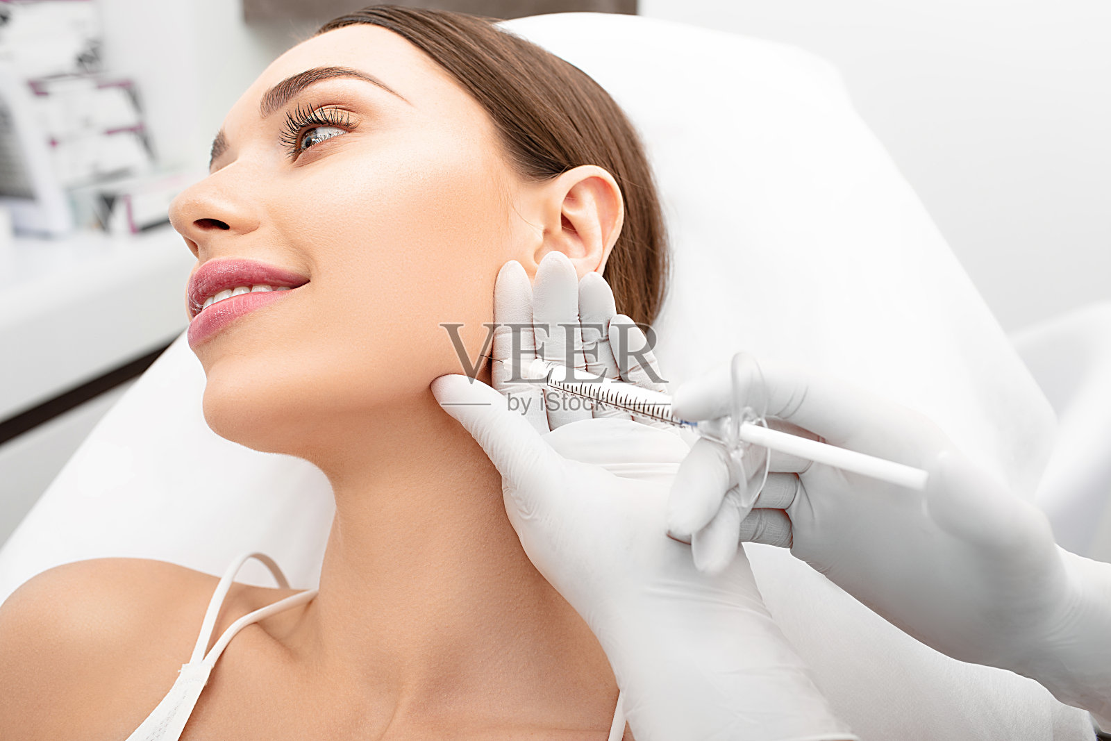 女性在收紧皮肤的过程中，将真皮填充剂注射到女性脸上。抗老化程序，面部年轻化照片摄影图片