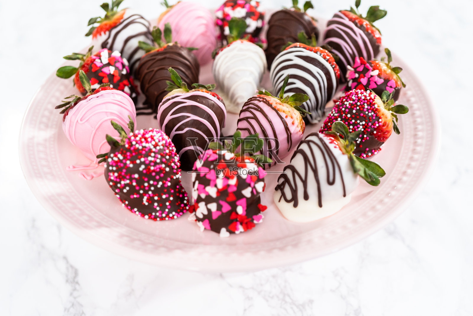 粉红色蛋糕架上的各种巧克力草莓。照片摄影图片