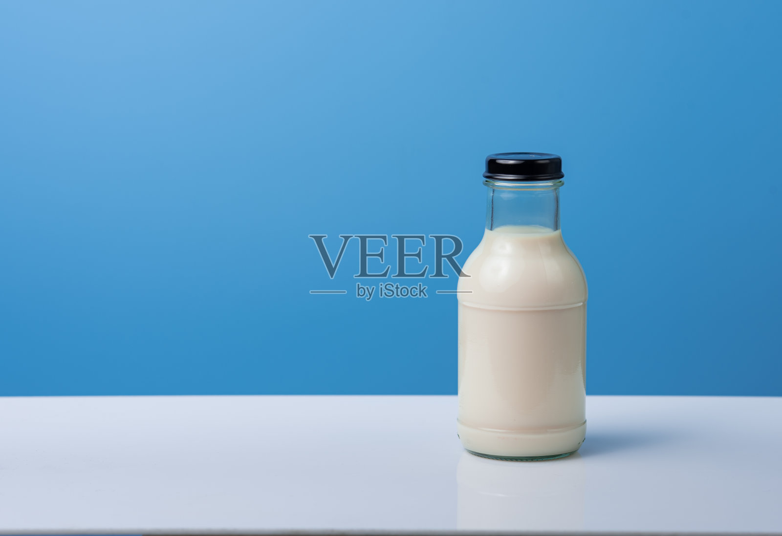 蓝色背景的牛奶瓶。照片摄影图片