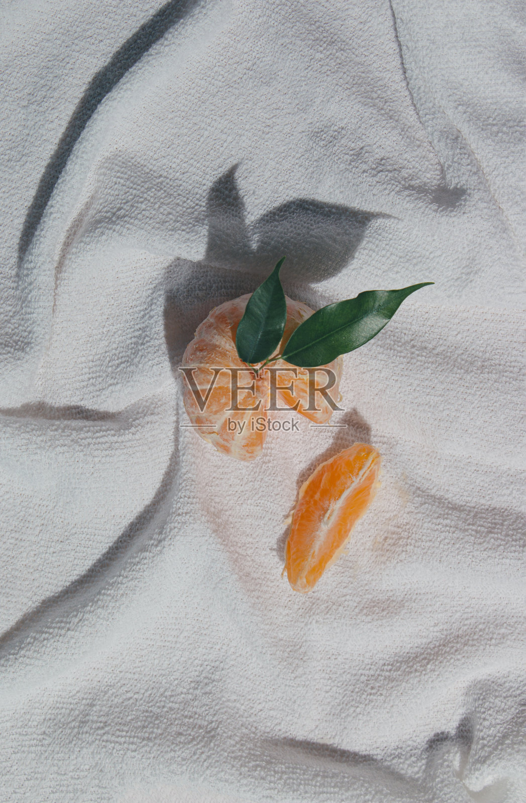 用白色沙滩毛巾擦去新鲜橙子或橘子皮。最小的夏天的概念。照片摄影图片