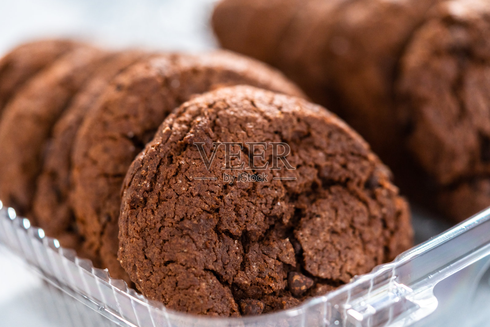 新鲜烘焙的双层巧克力饼干装在塑料容器里。照片摄影图片