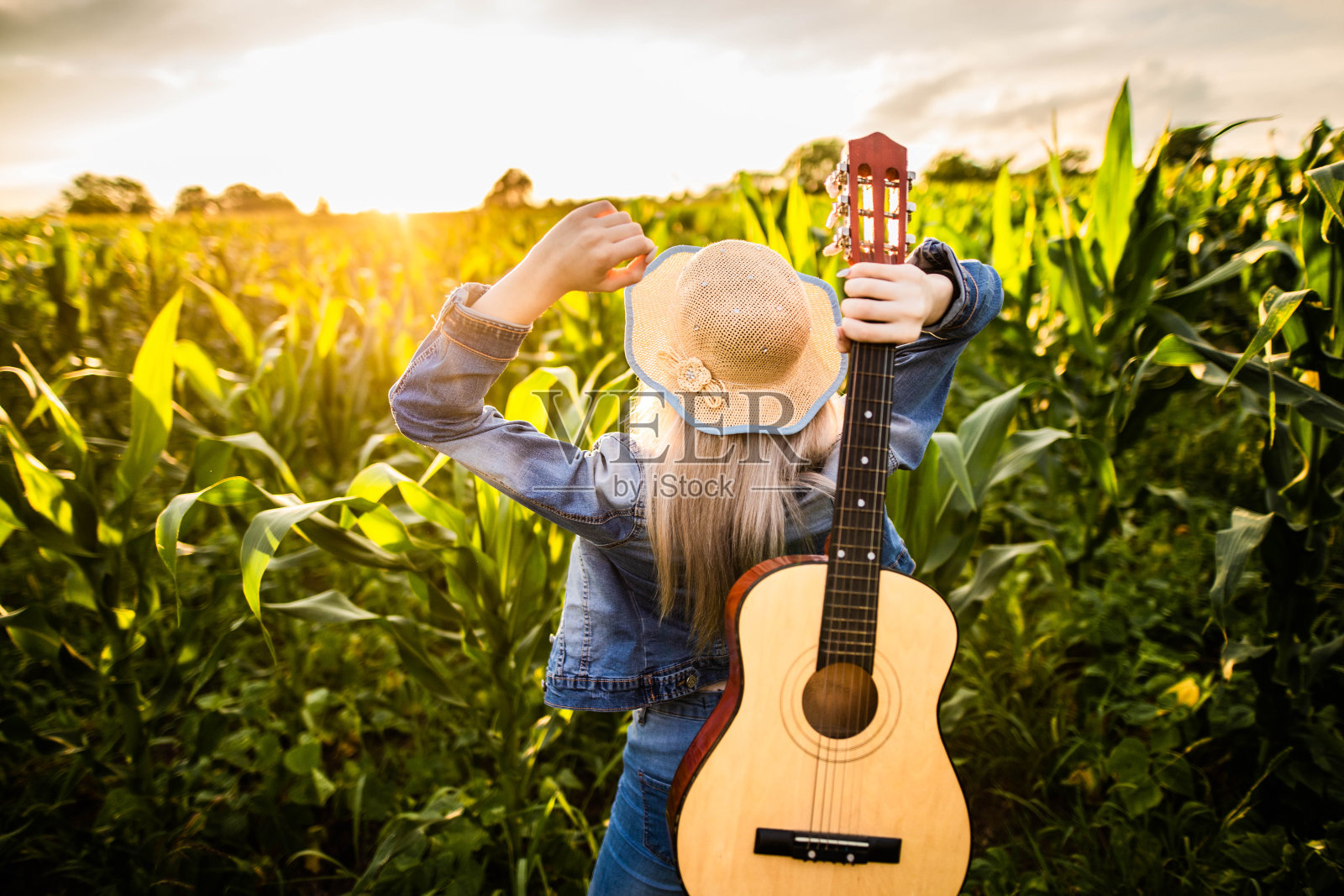 后视图美丽的女孩享受日落在田野照片摄影图片