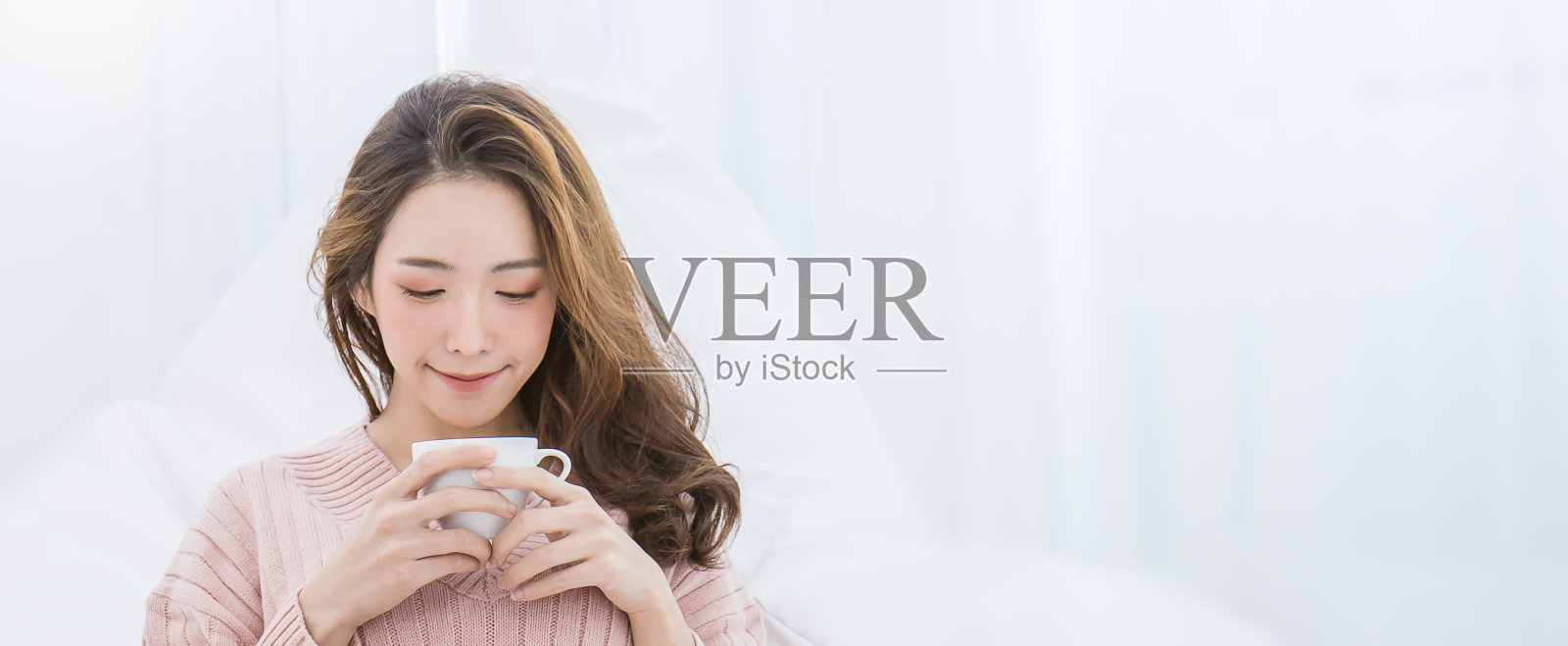 年轻美丽的亚洲女人她的手捧着一杯咖啡，在她的白色卧室冬天的早上时间。快乐愉悦，在寒冷的冬天放松概念横幅照片摄影图片