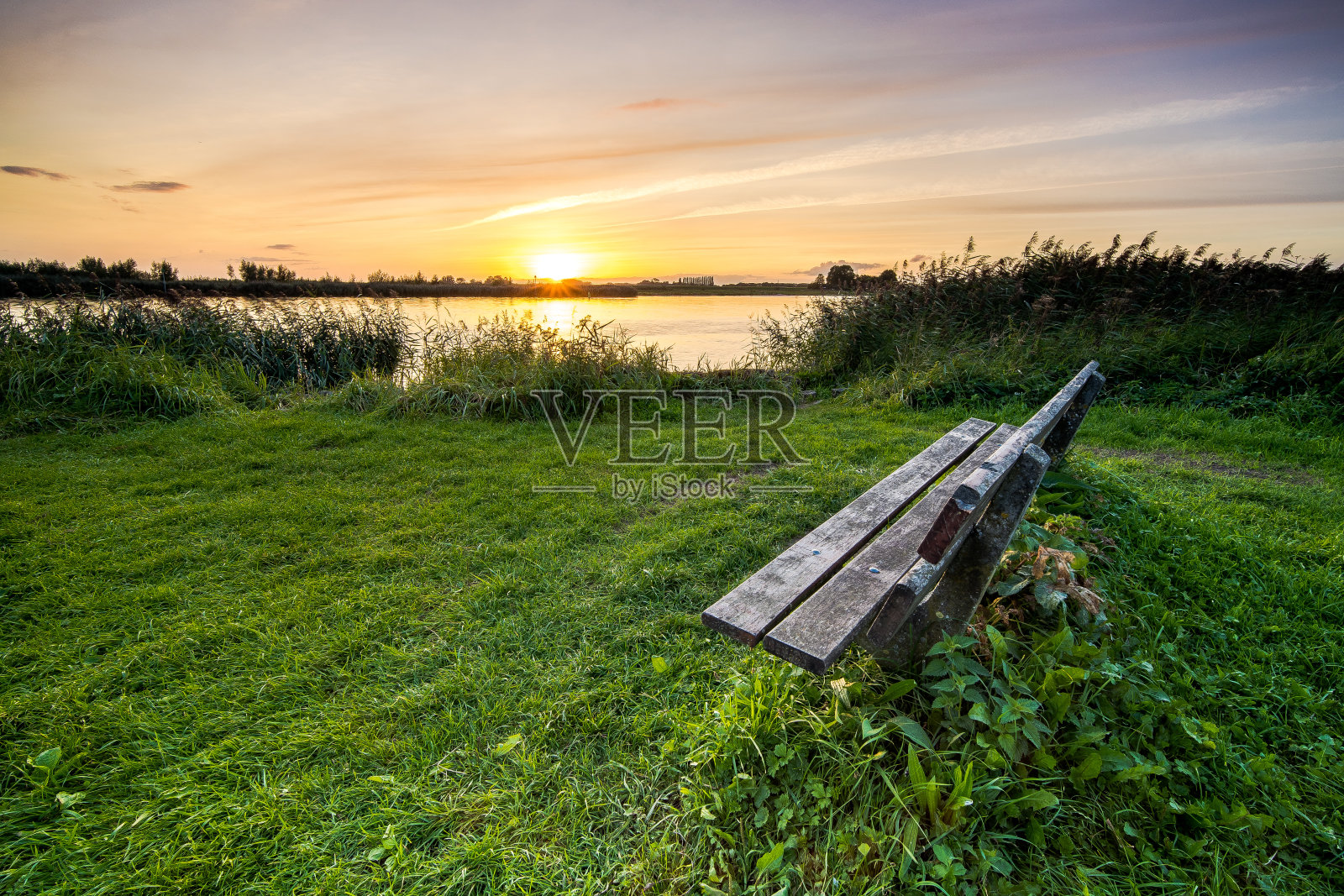 日落时荷兰河岸边的木制休息凳照片摄影图片