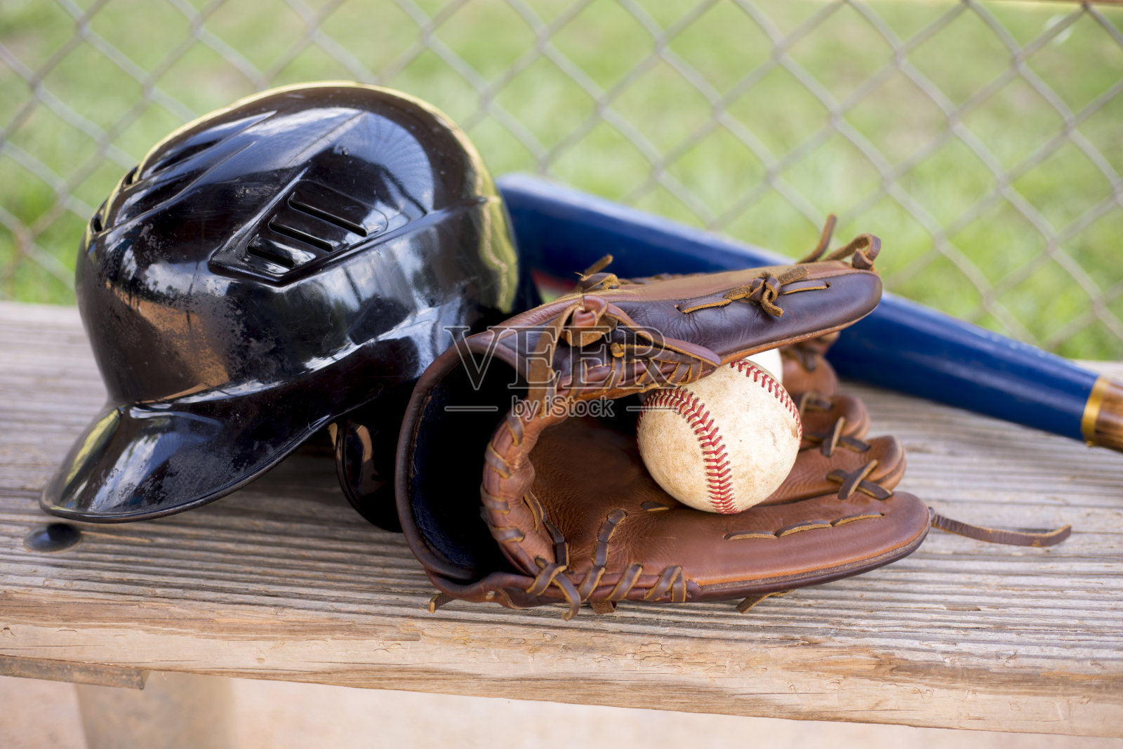 棒球赛季到了。教练席上的球棒、手套、头盔和球。照片摄影图片
