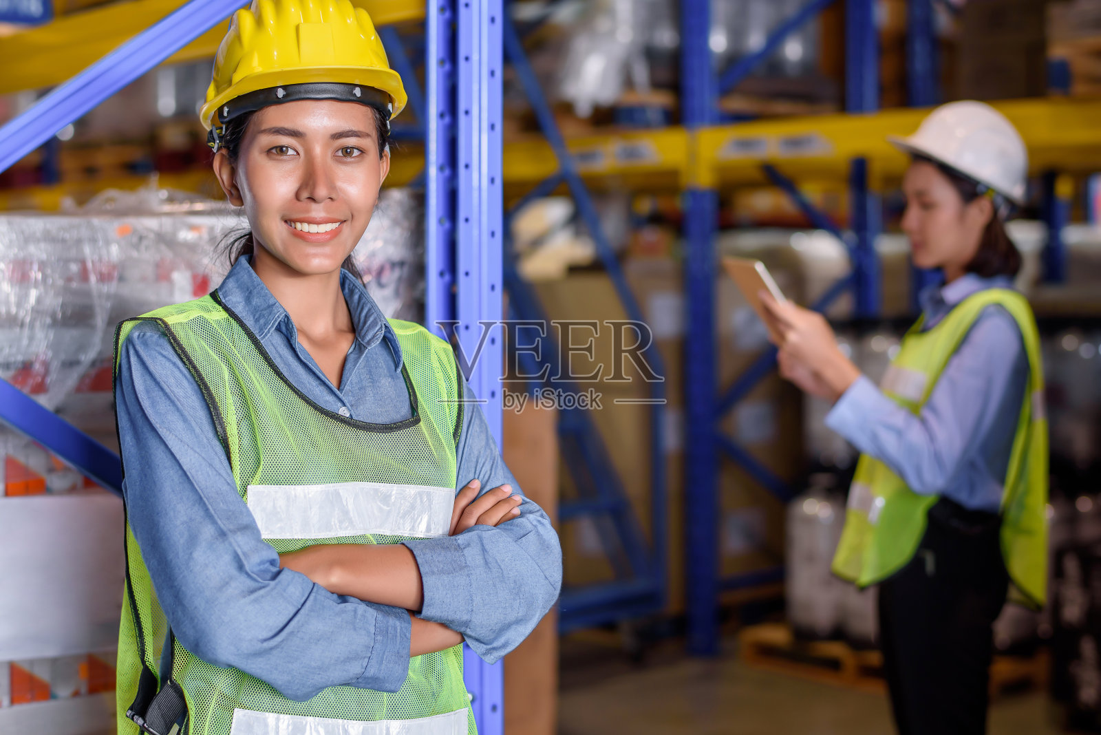 戴安全帽的仓库女工站在货物或商品仓库，检查货物从货船的进口和出口的控制装载。团队合作理念照片摄影图片