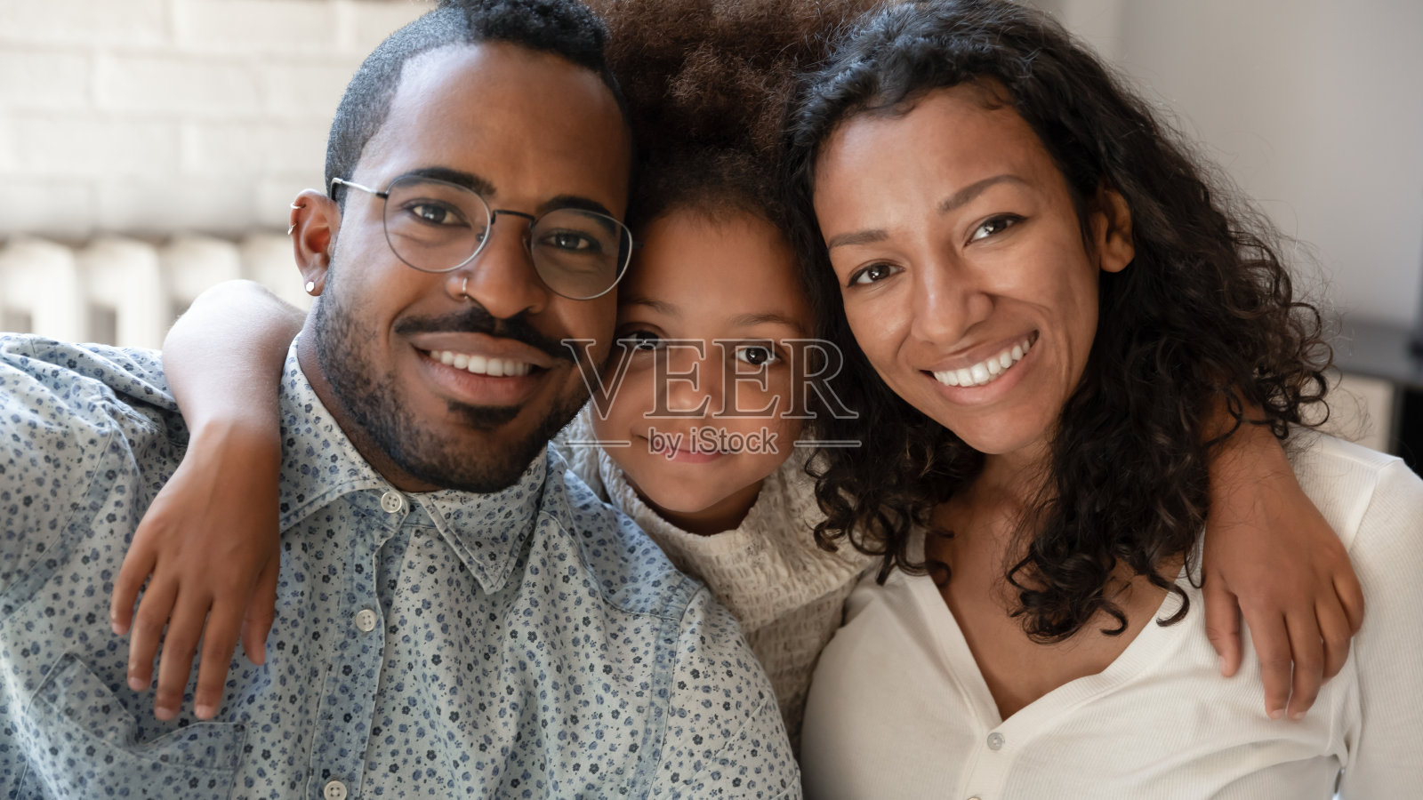 微笑的非洲裔小女孩拥抱着混血儿父母。照片摄影图片